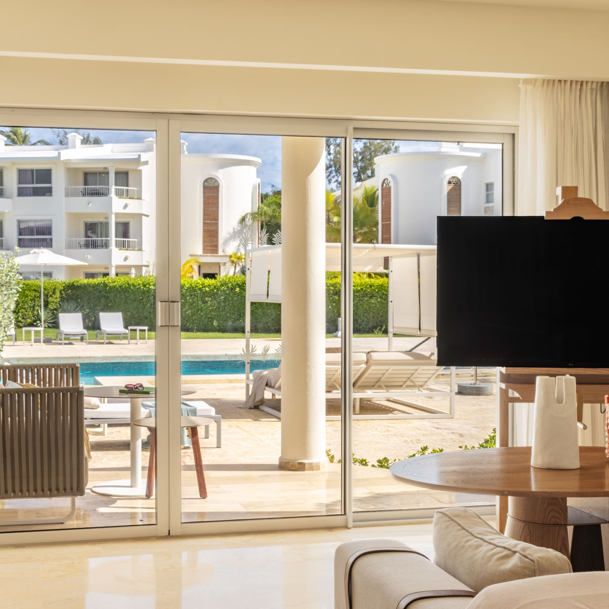 Luxurious resort living room with pool view through sliding glass doors.
