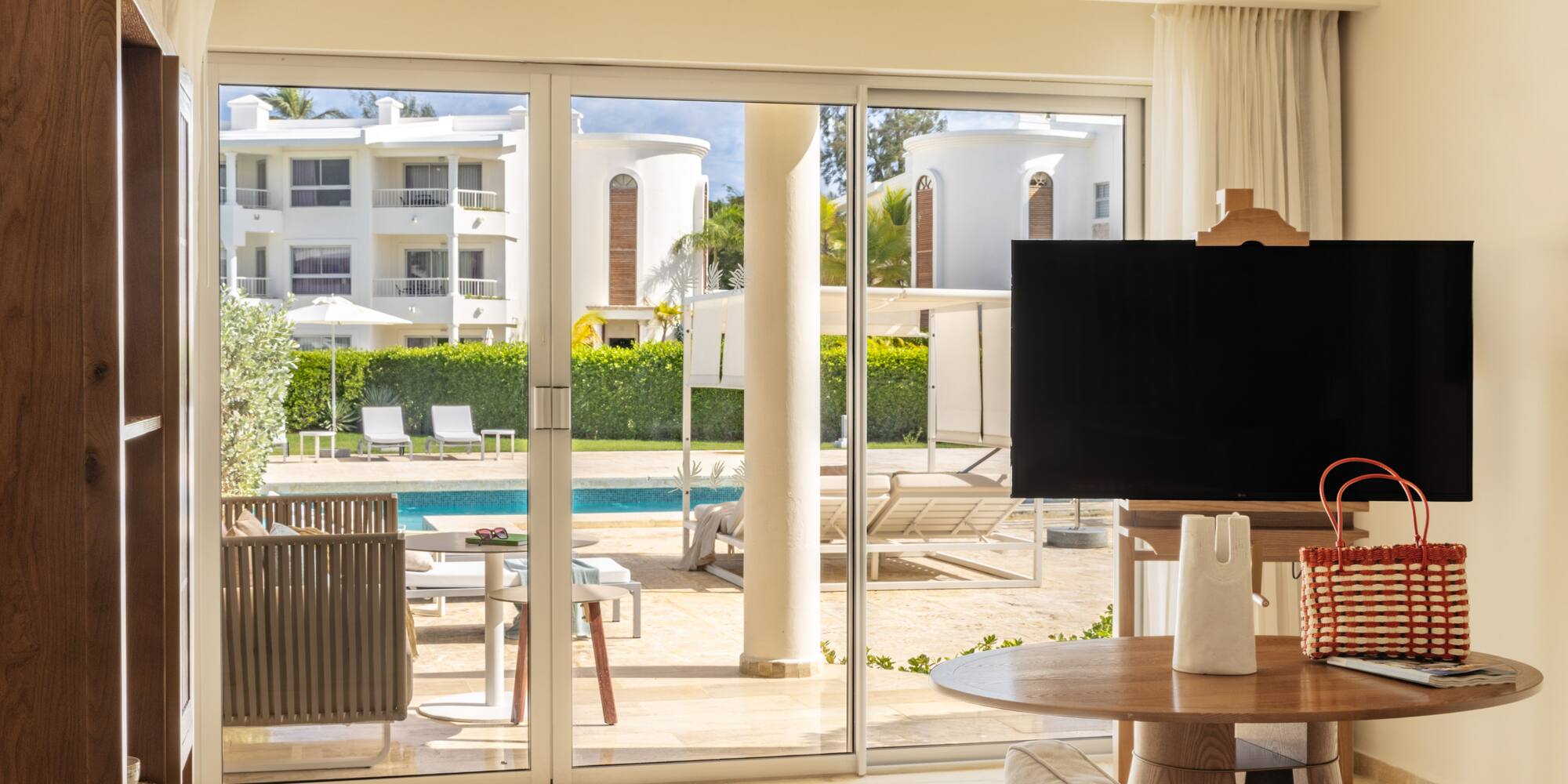 Luxurious resort living room with pool view through sliding glass doors.