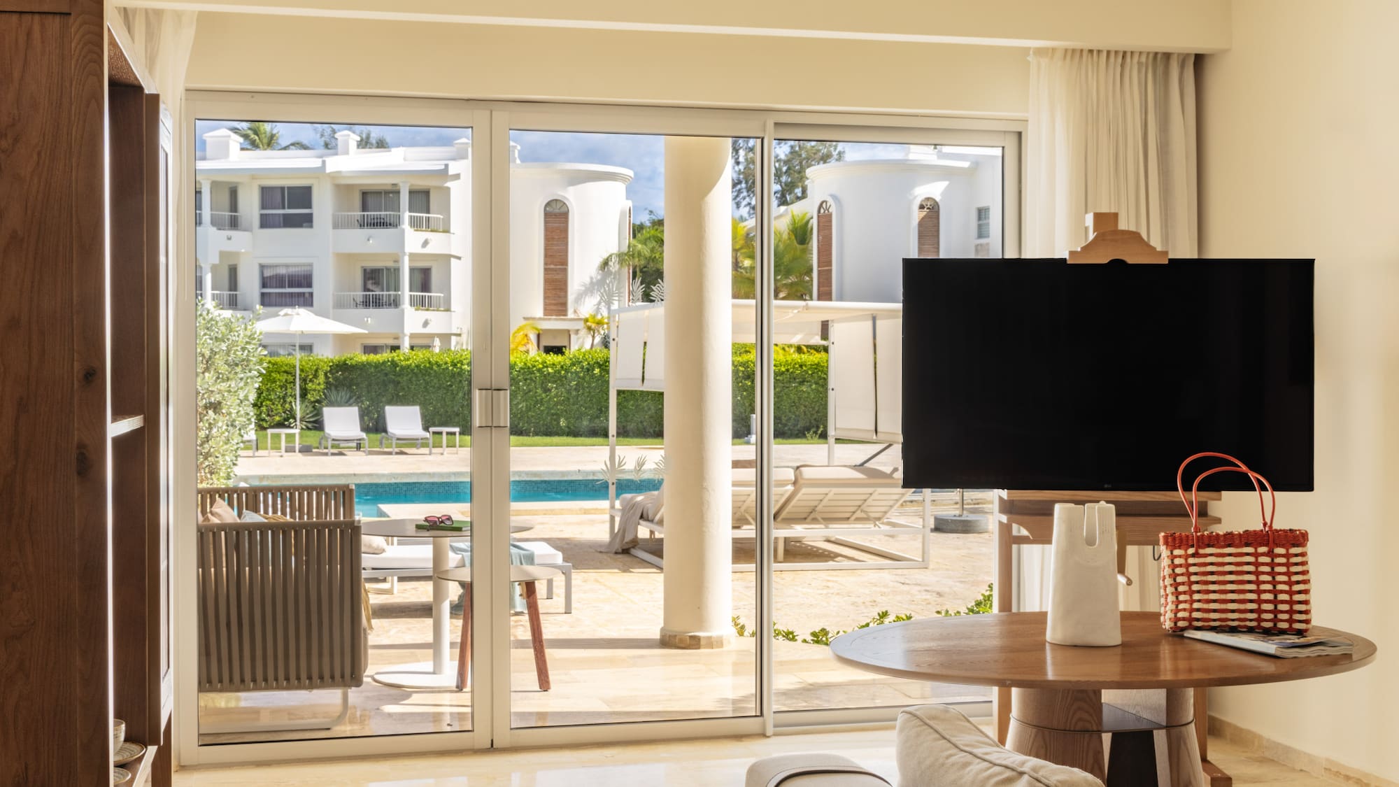 Luxurious resort living room with pool view through sliding glass doors.
