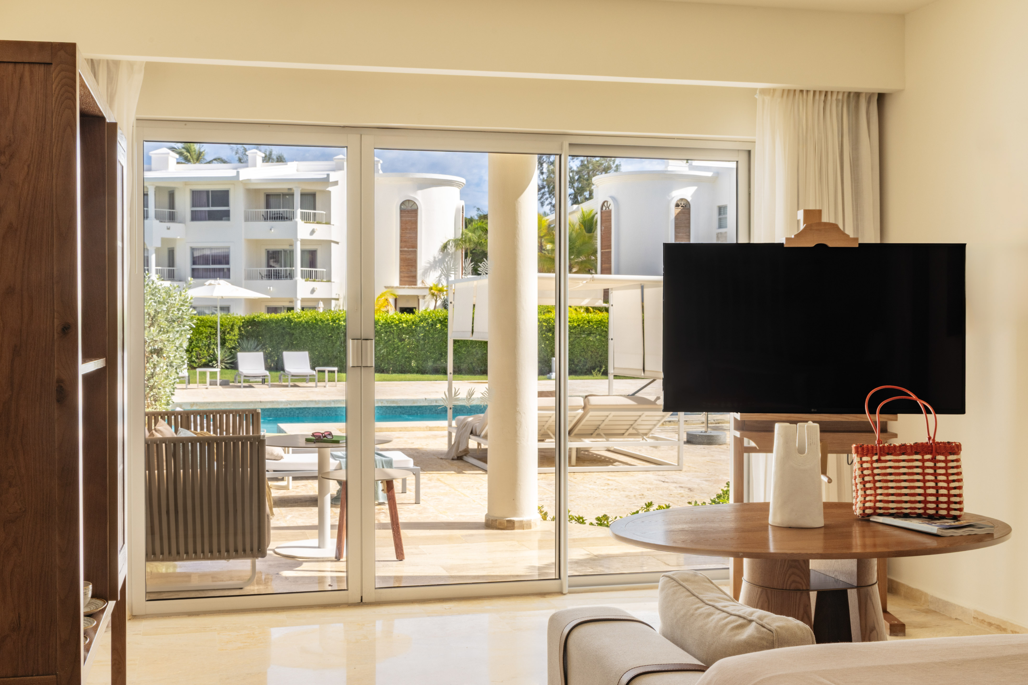 Luxurious resort living room with pool view through sliding glass doors.