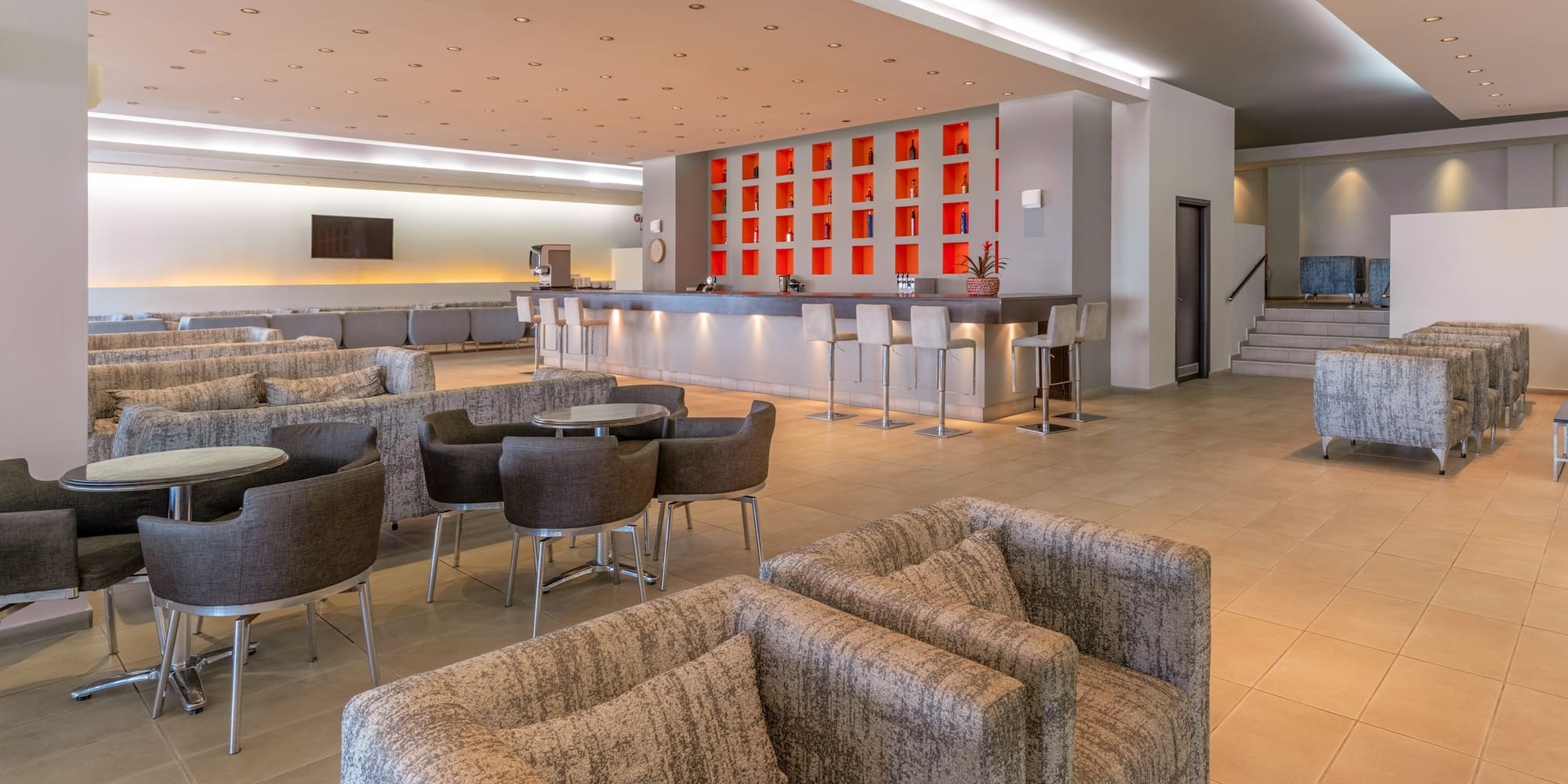 Modern hotel lounge bar with red accent wall, ample seating, and stylish decor.