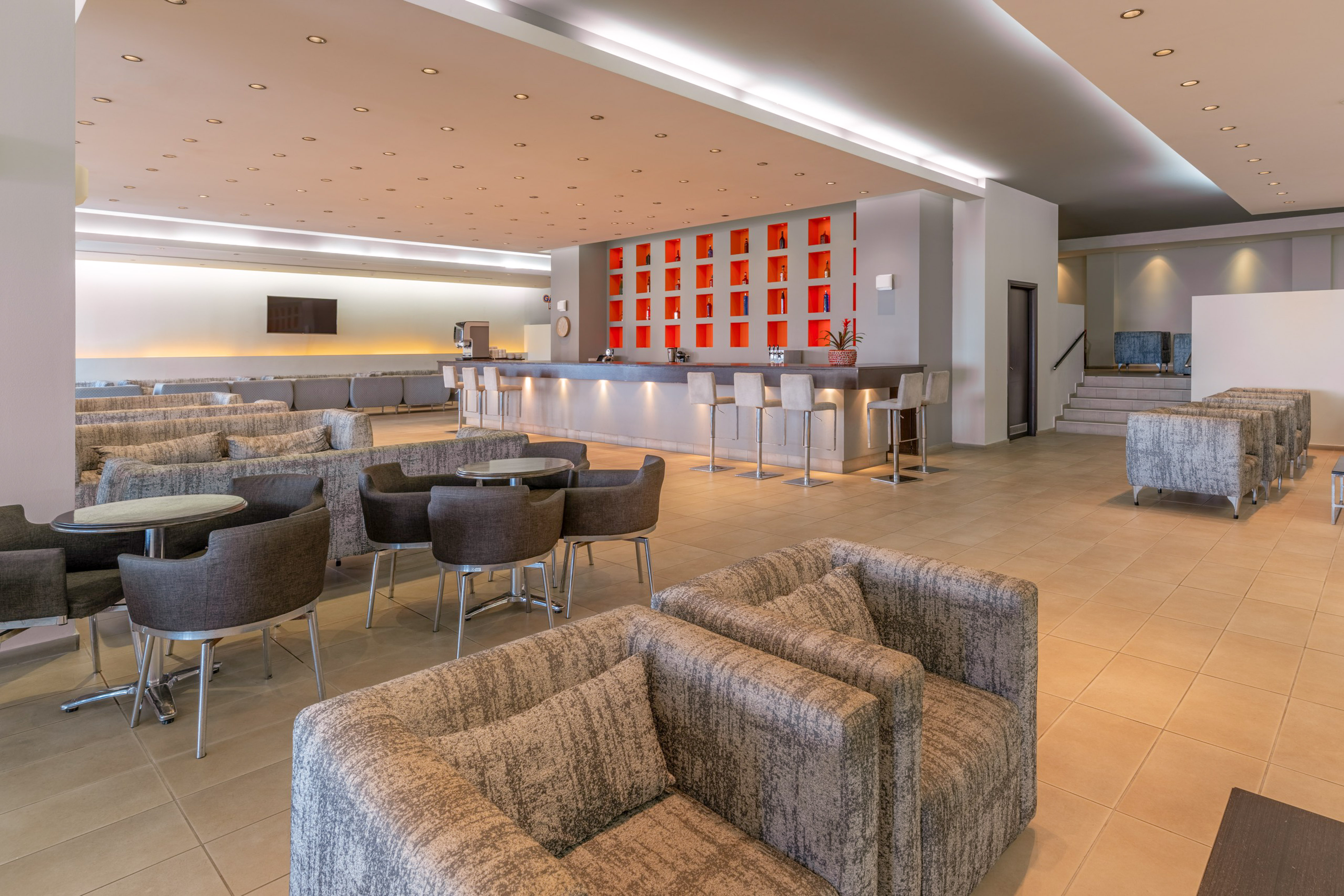 Modern hotel lounge bar with red accent wall, ample seating, and stylish decor.