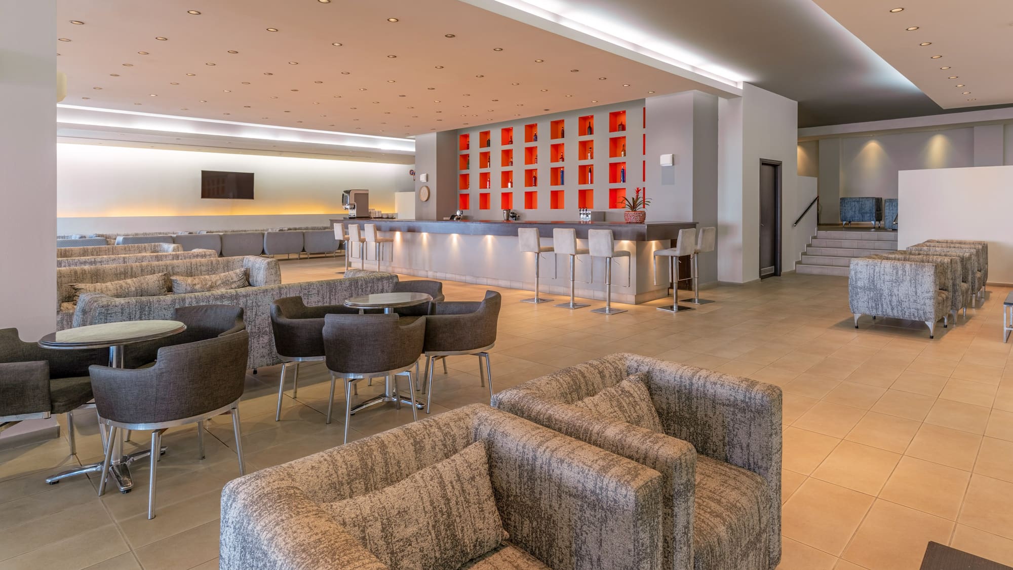 Modern hotel lounge bar with red accent wall, ample seating, and stylish decor.