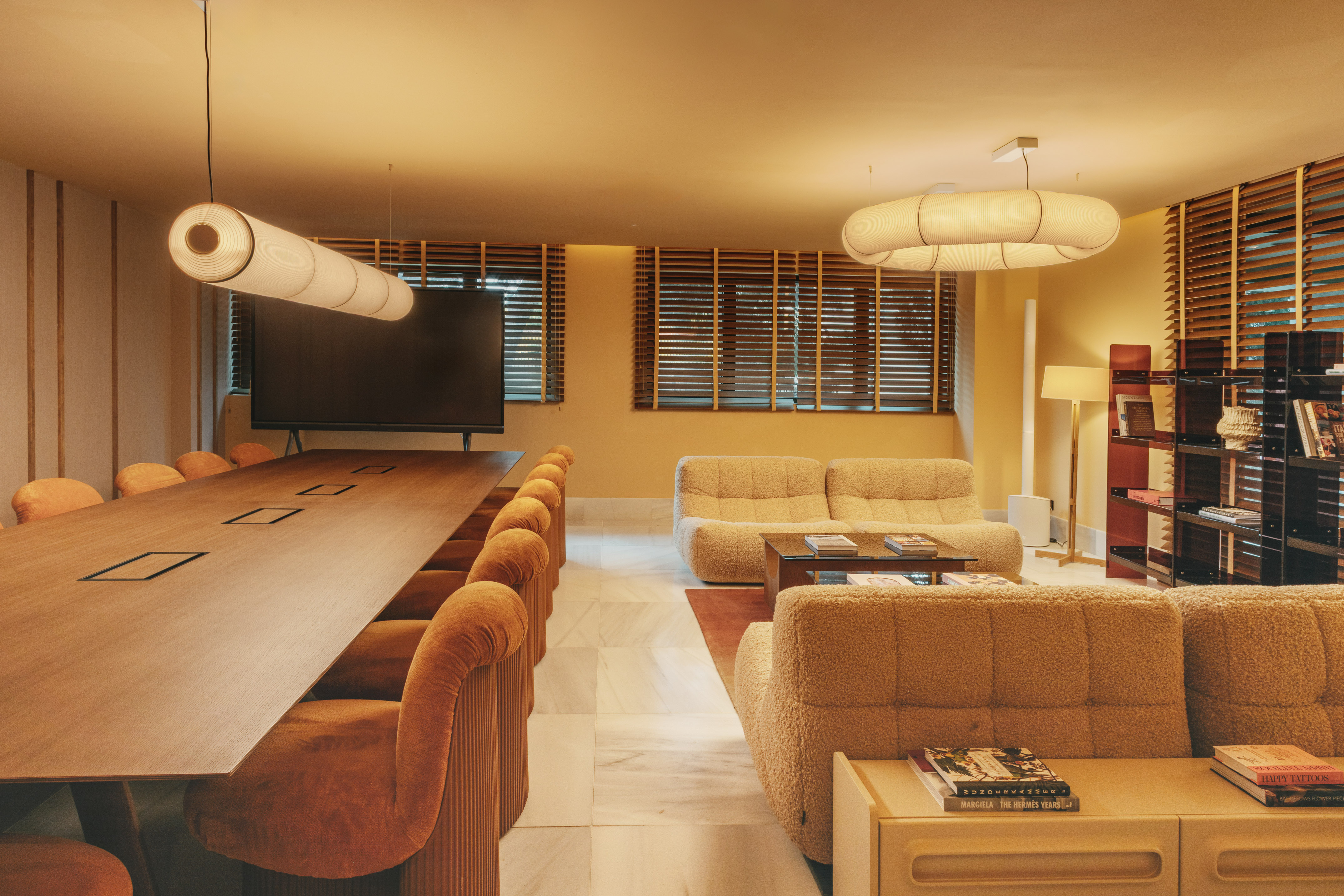 Modern office meeting room and lounge with warm lighting, plush seating.