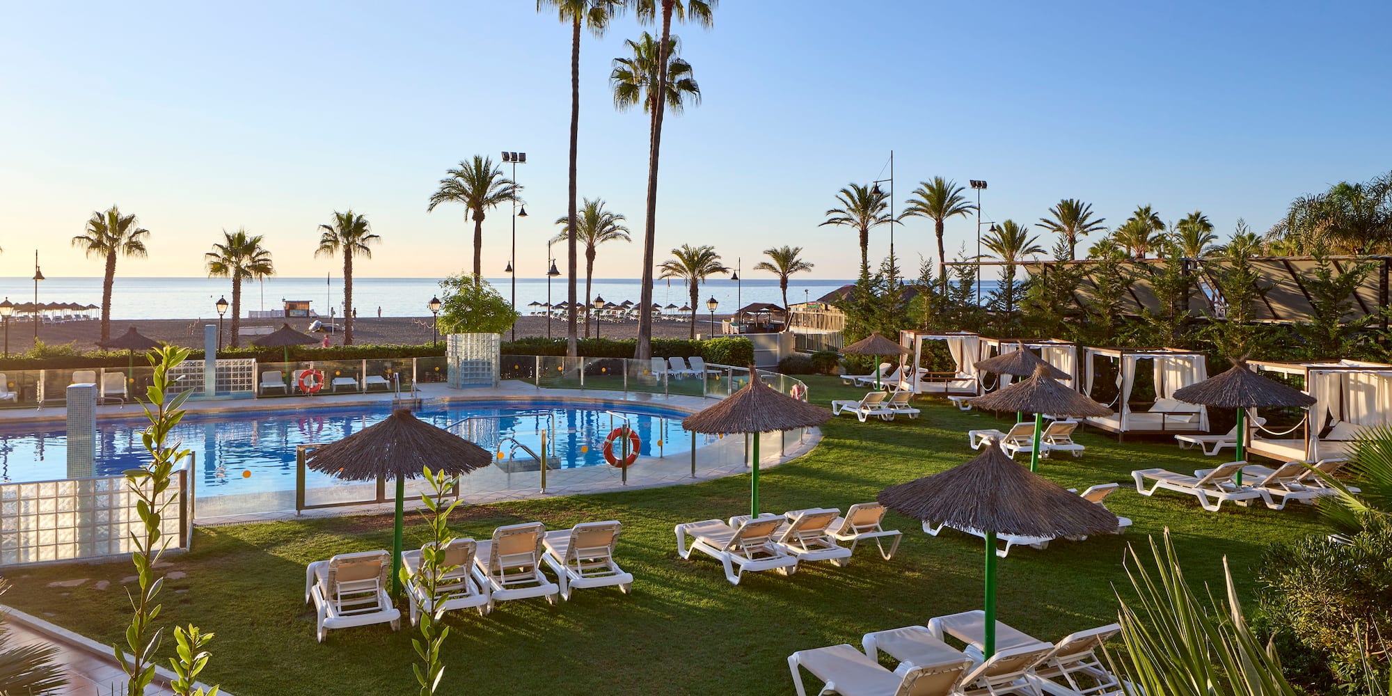 a pool with lounge chairs and umbrellas and palm trees