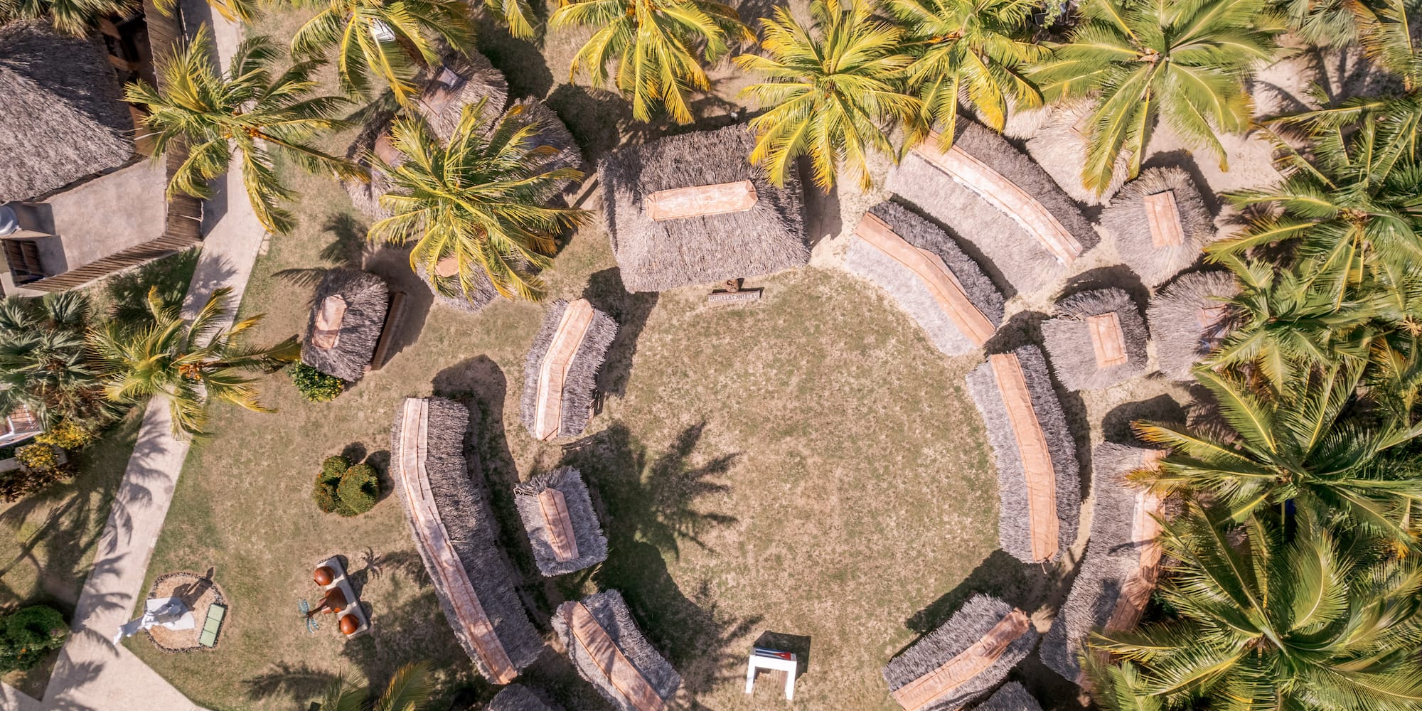 a circular area with straw huts and palm trees