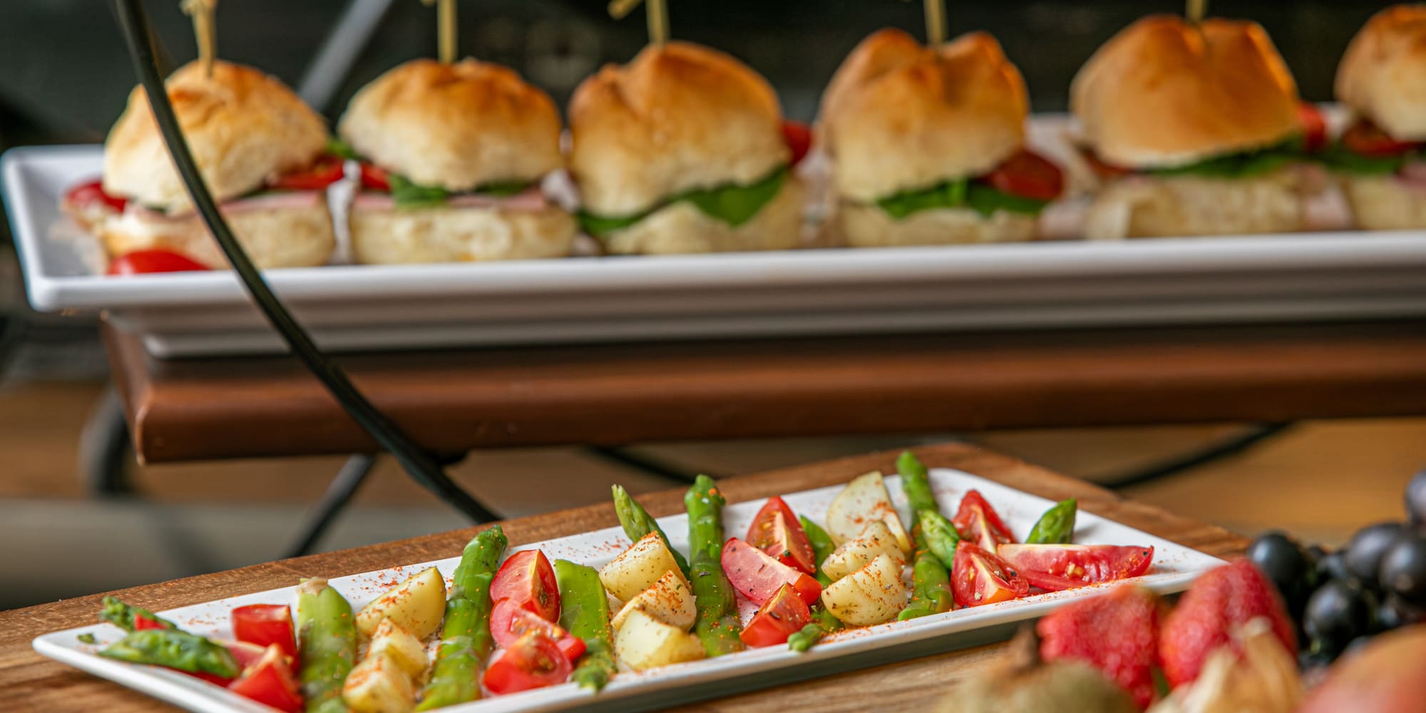 Mini sliders on tiered stand, with asparagus, potato, tomato salad.