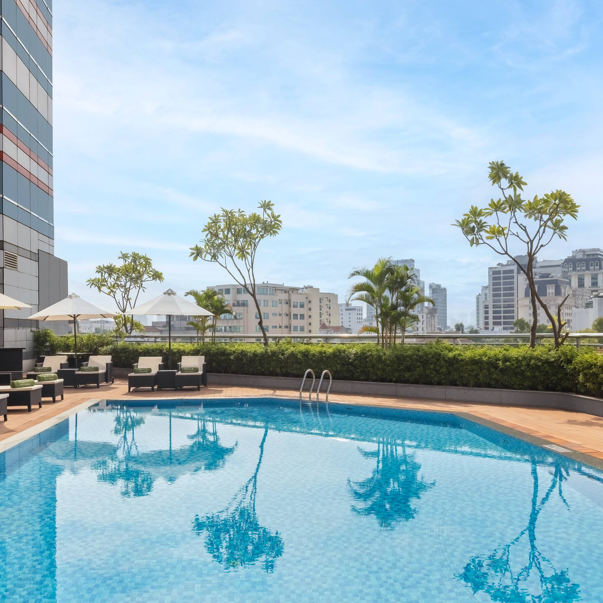 a pool with chairs and umbrellas on a rooftop