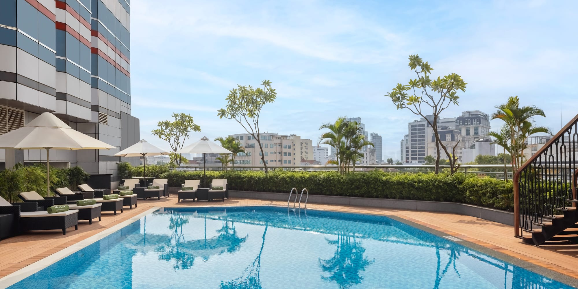 a pool with chairs and umbrellas on a rooftop