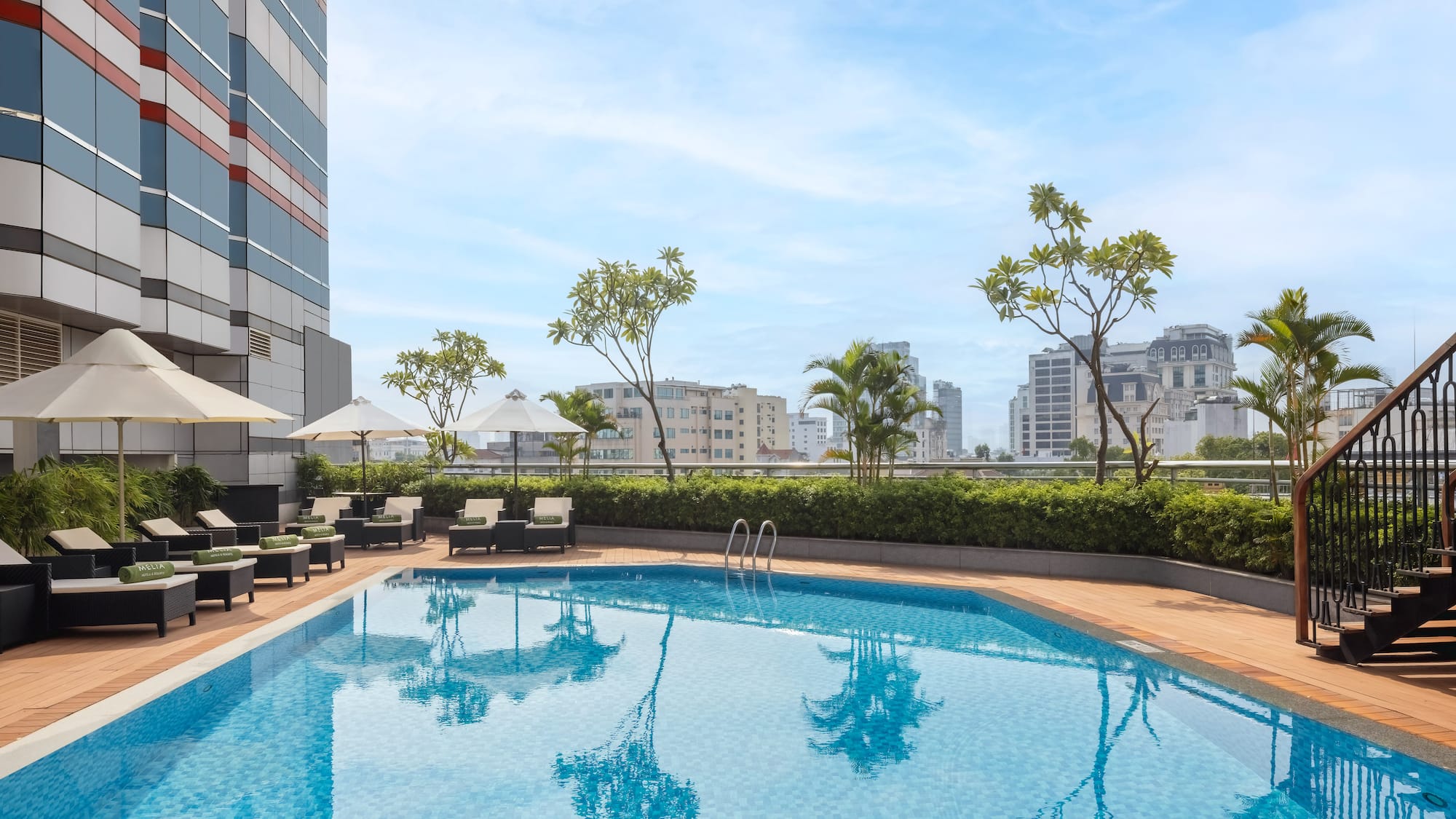 a pool with chairs and umbrellas on a rooftop