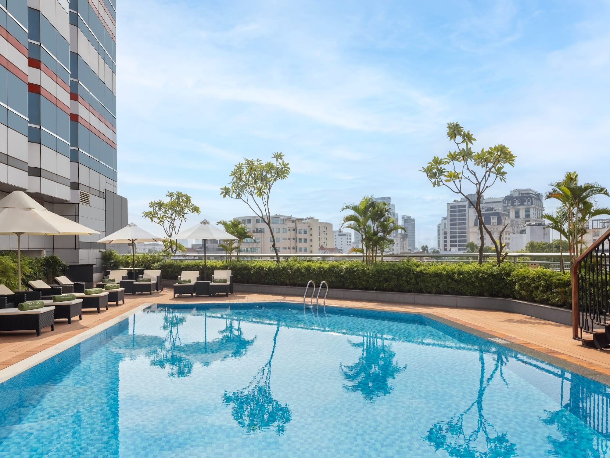 a pool with chairs and umbrellas on a rooftop