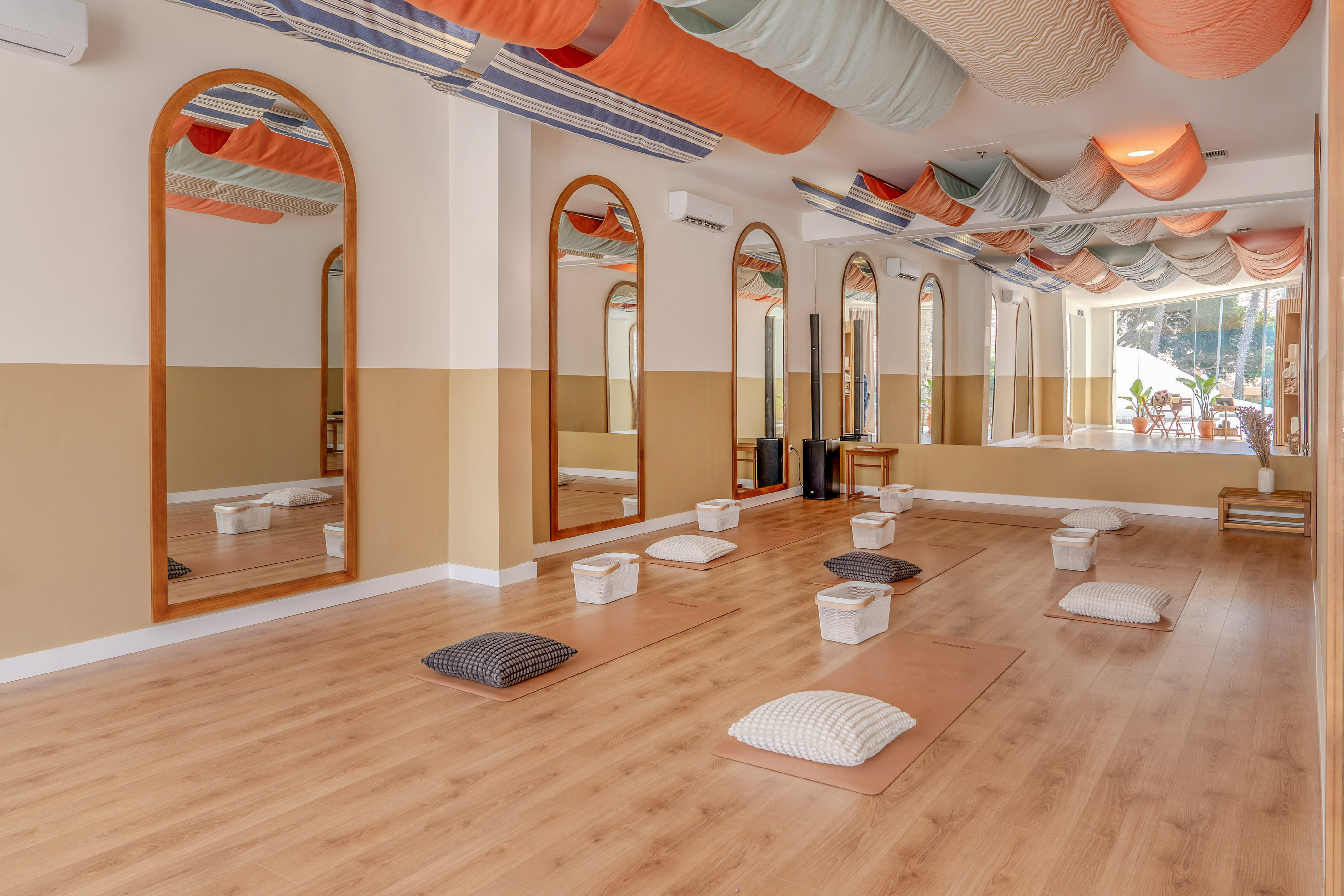 Modern yoga and meditation studio with colorful ceiling drapes, mats, and mirrors.