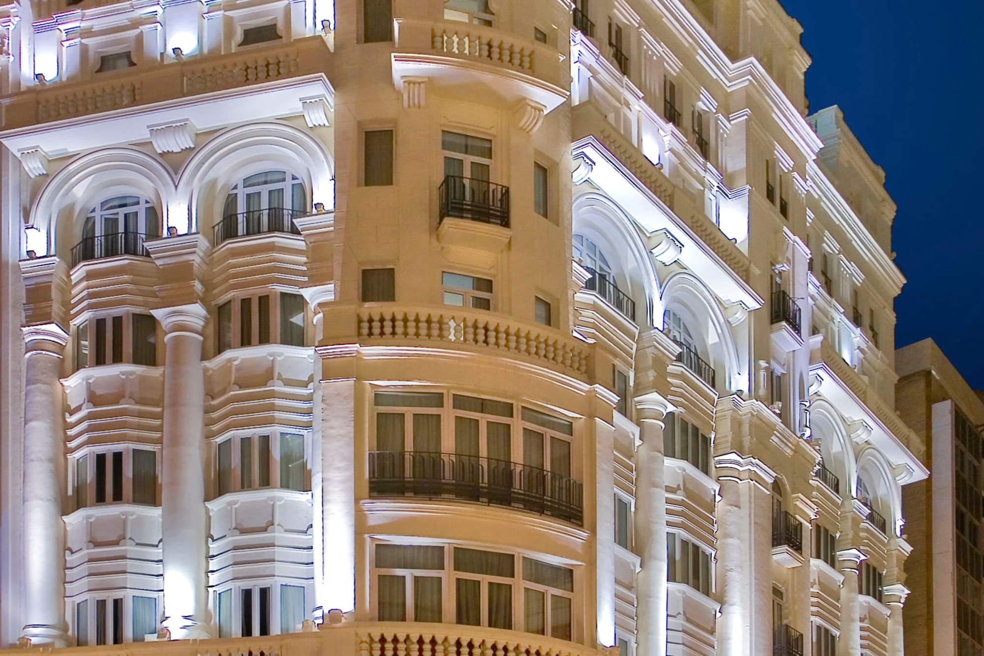 Illuminated Melia Plaza hotel building at night with classic architecture.