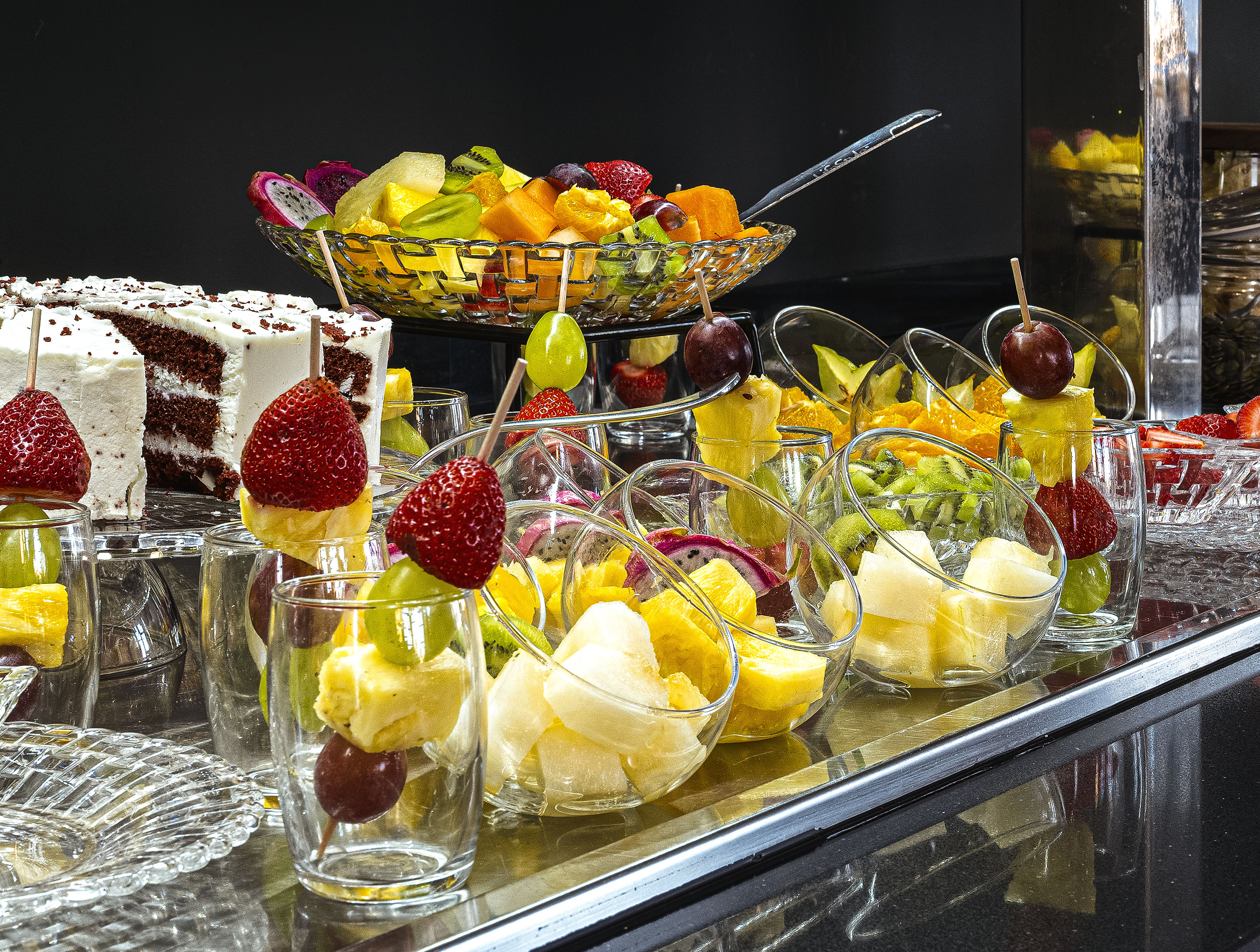 Fresh fruit buffet: mixed fruit salad, individual skewers, and red velvet cake.