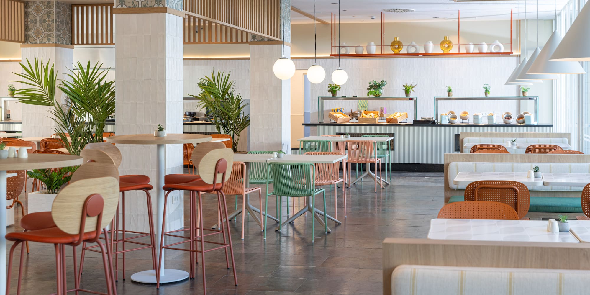 Modern hotel restaurant with buffet, colorful chairs, and cozy booths.
