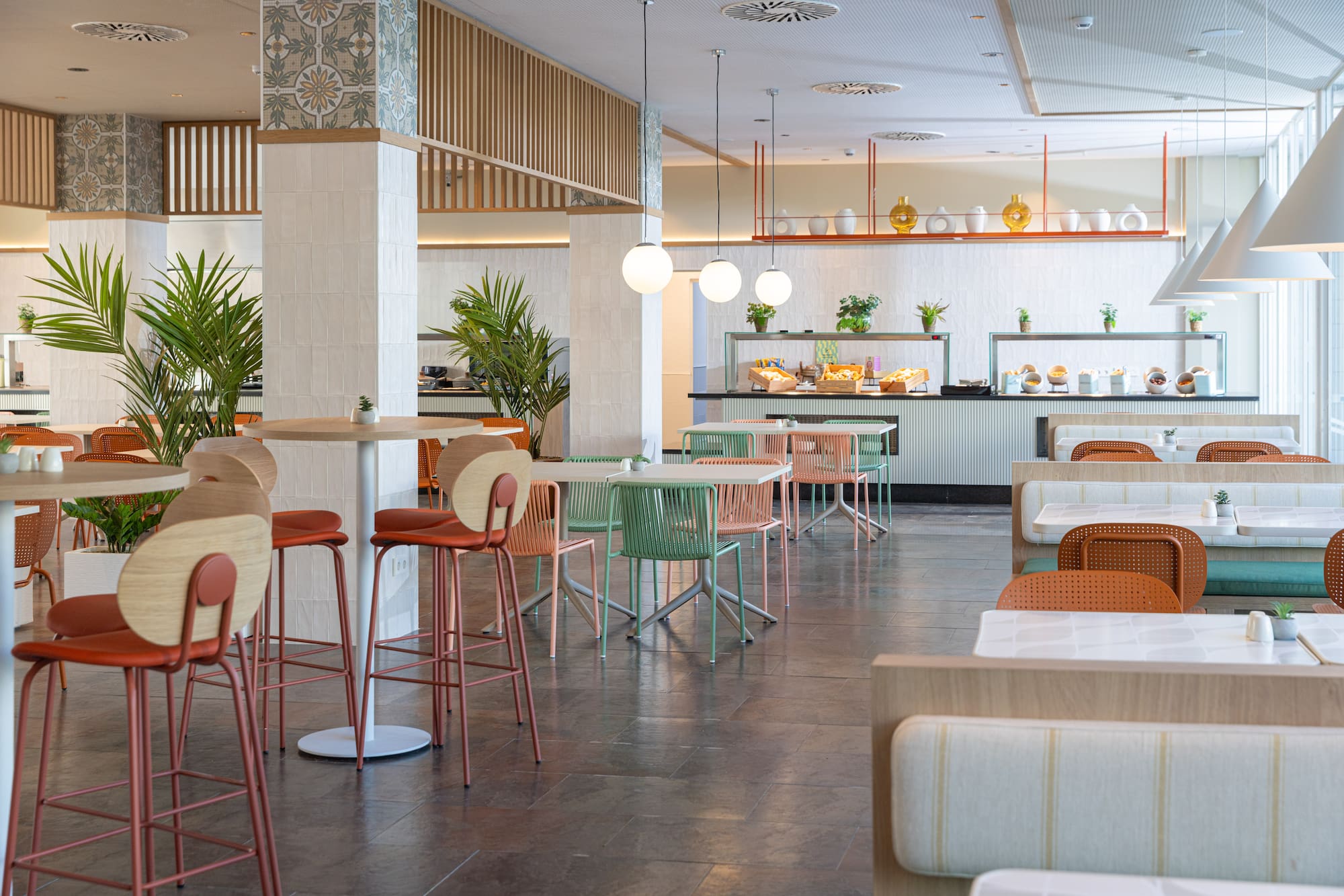 Modern hotel restaurant with buffet, colorful chairs, and cozy booths.