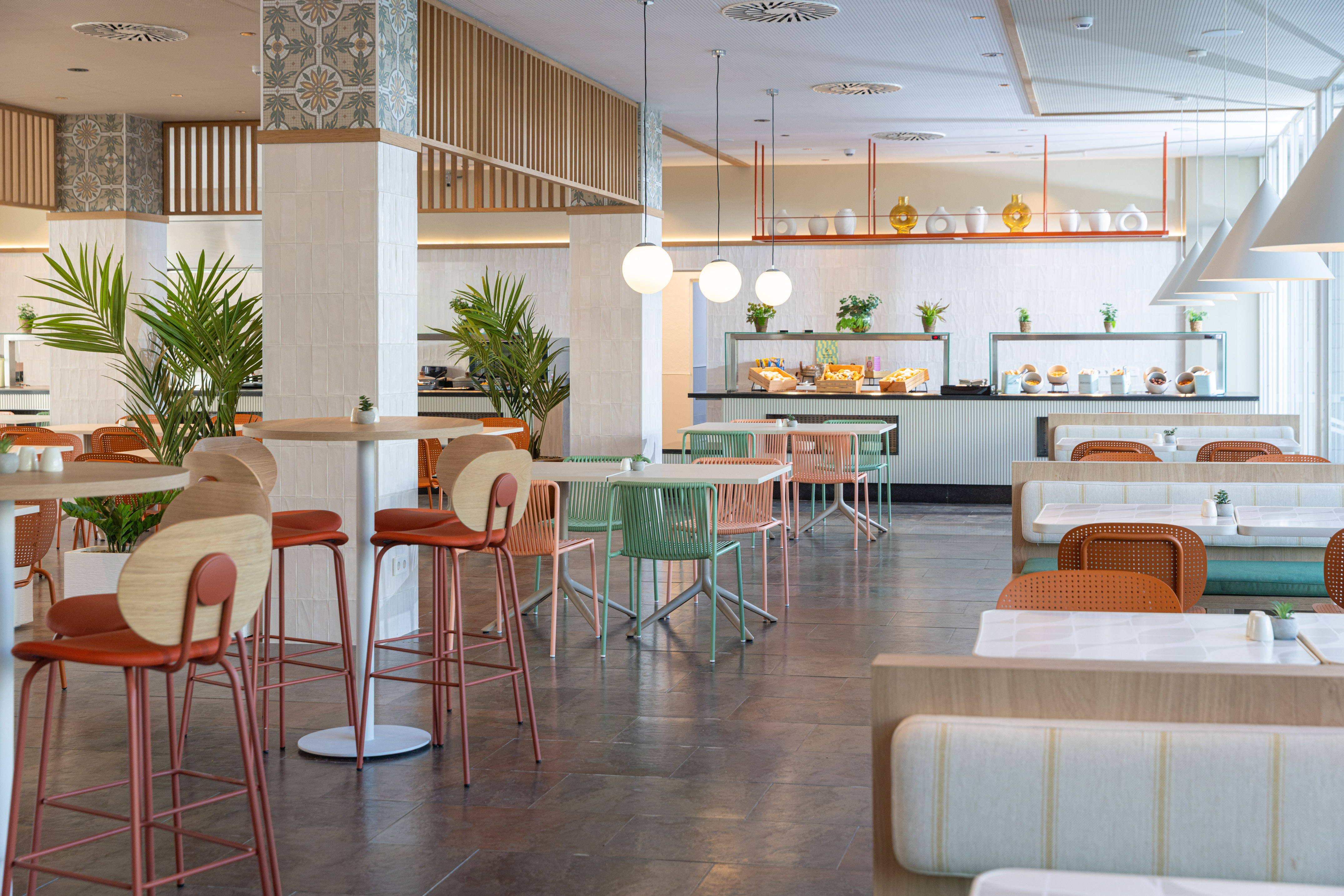Modern hotel restaurant with buffet, colorful chairs, and cozy booths.