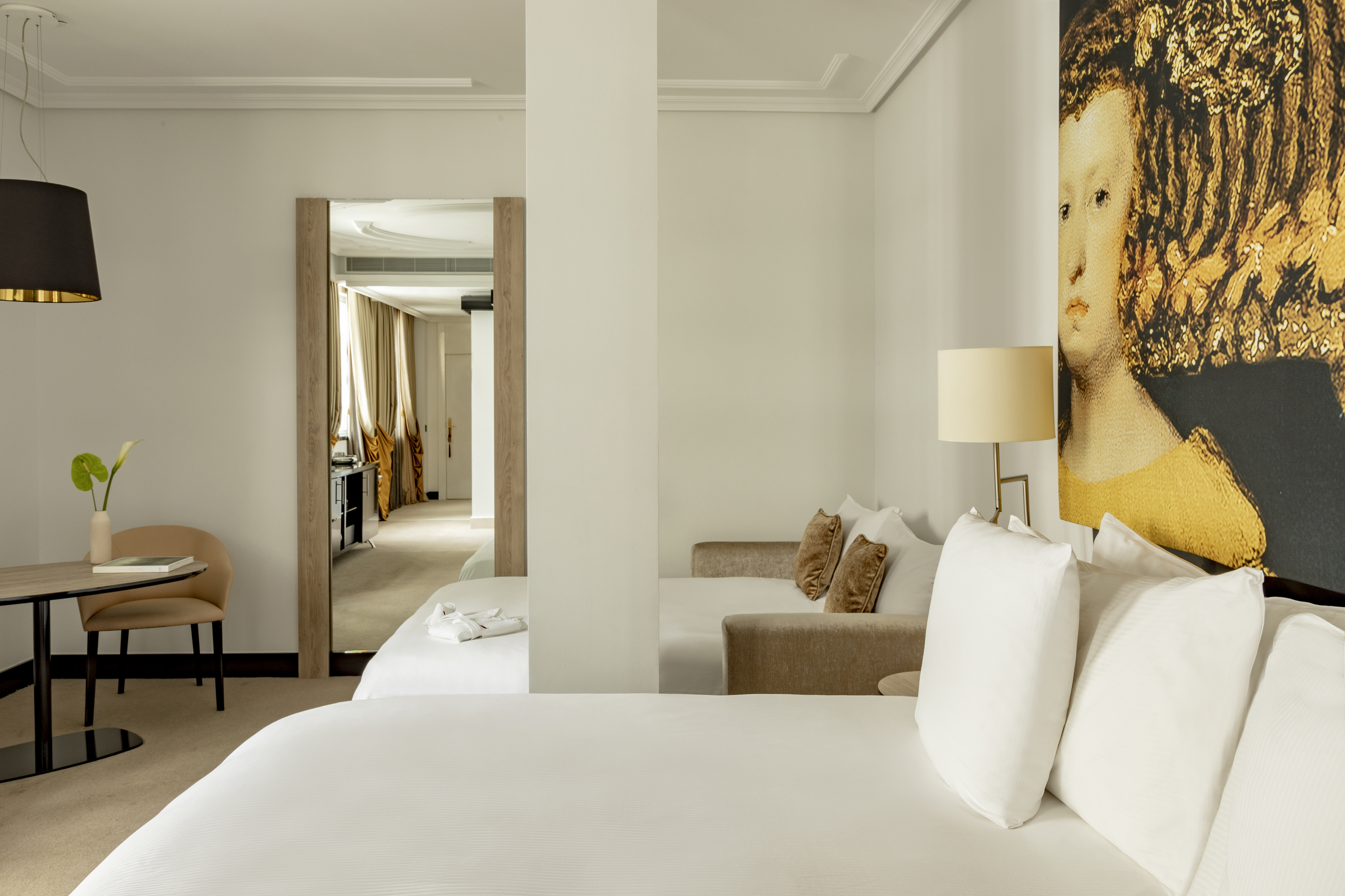 Elegant hotel suite with a large bed, lounge area, and modern art.