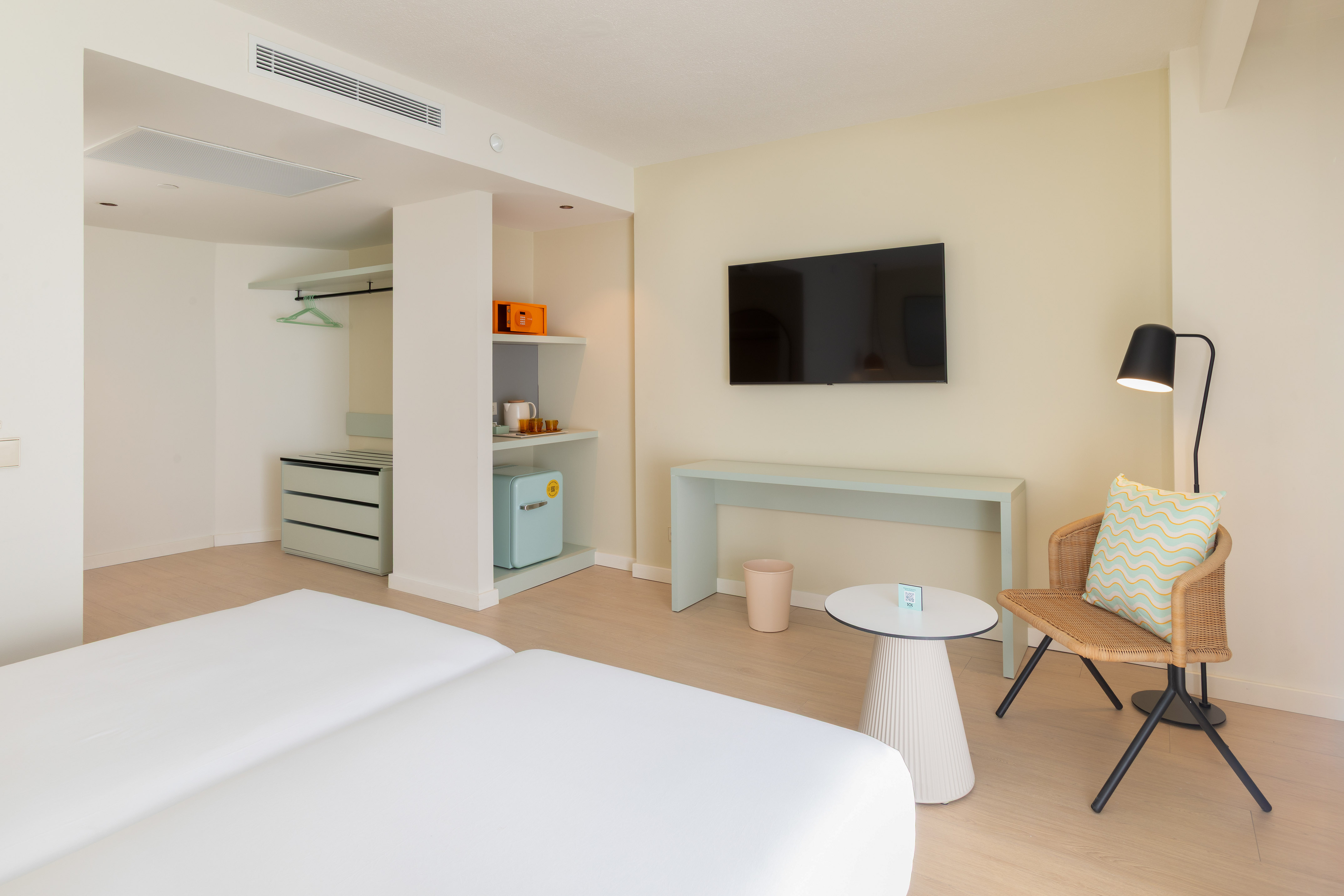 Light, airy modern hotel room with twin beds, TV, and minibar.