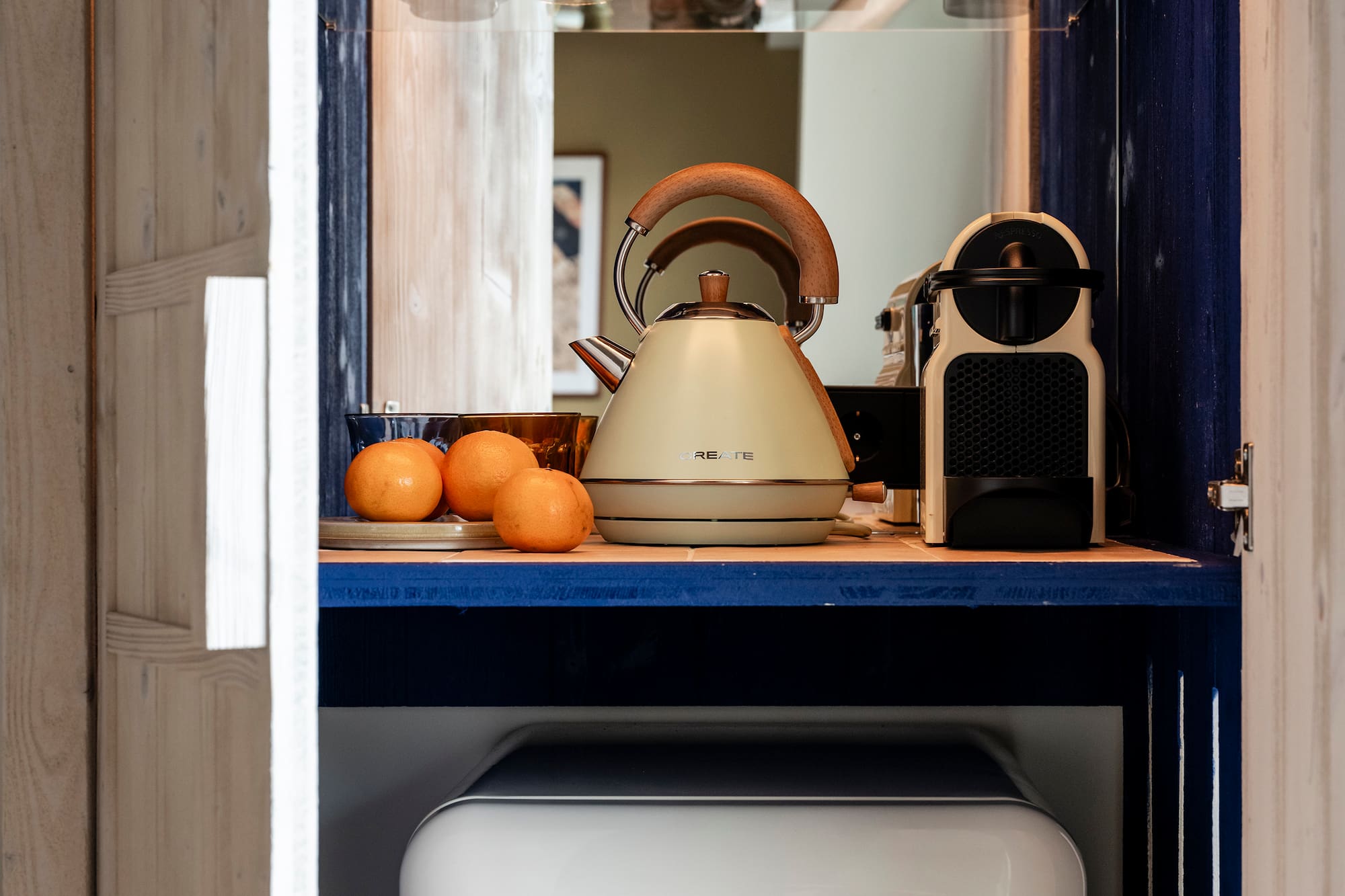 a kitchen cabinet with a white refrigerator and a tea kettle