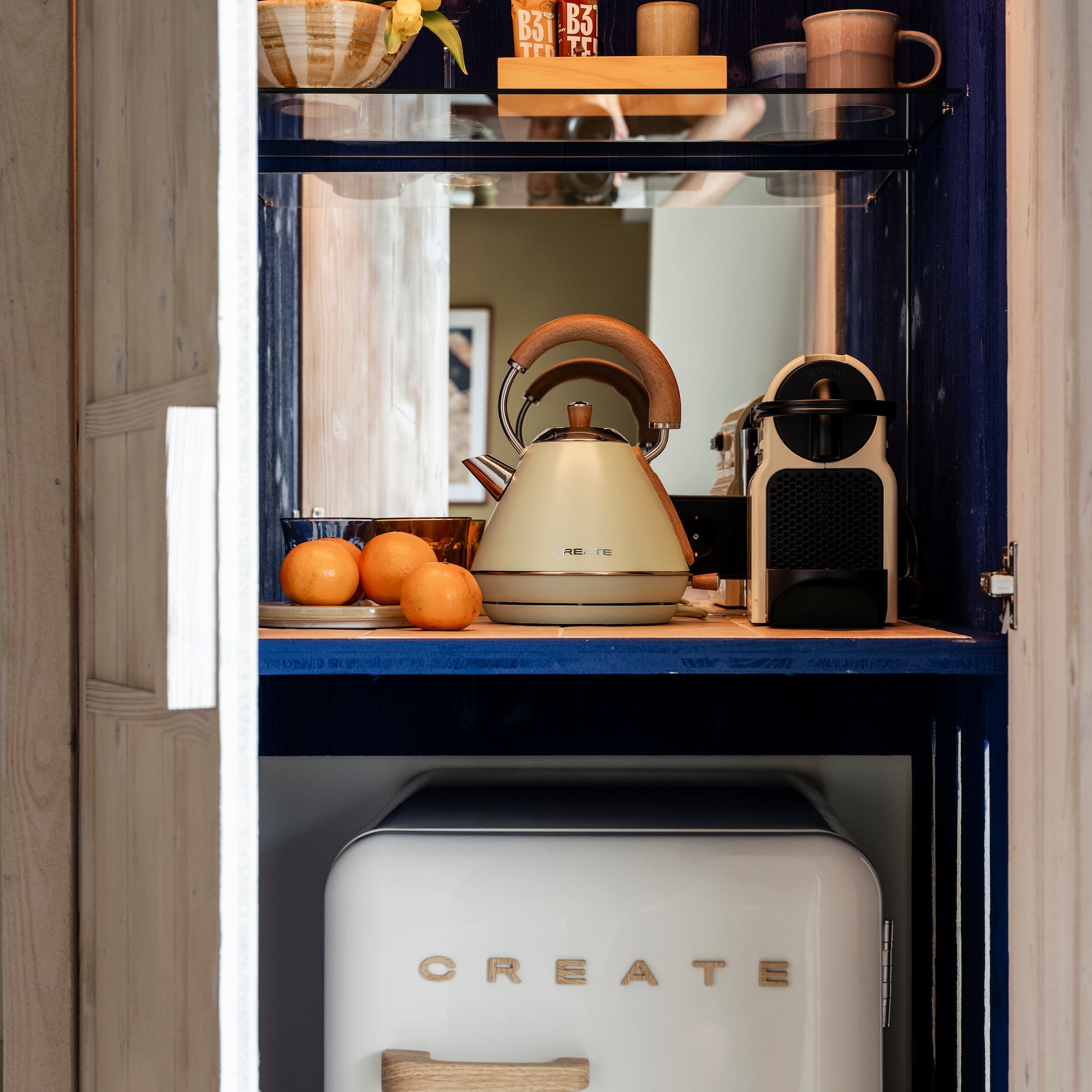 a kitchen cabinet with a white refrigerator and a tea kettle