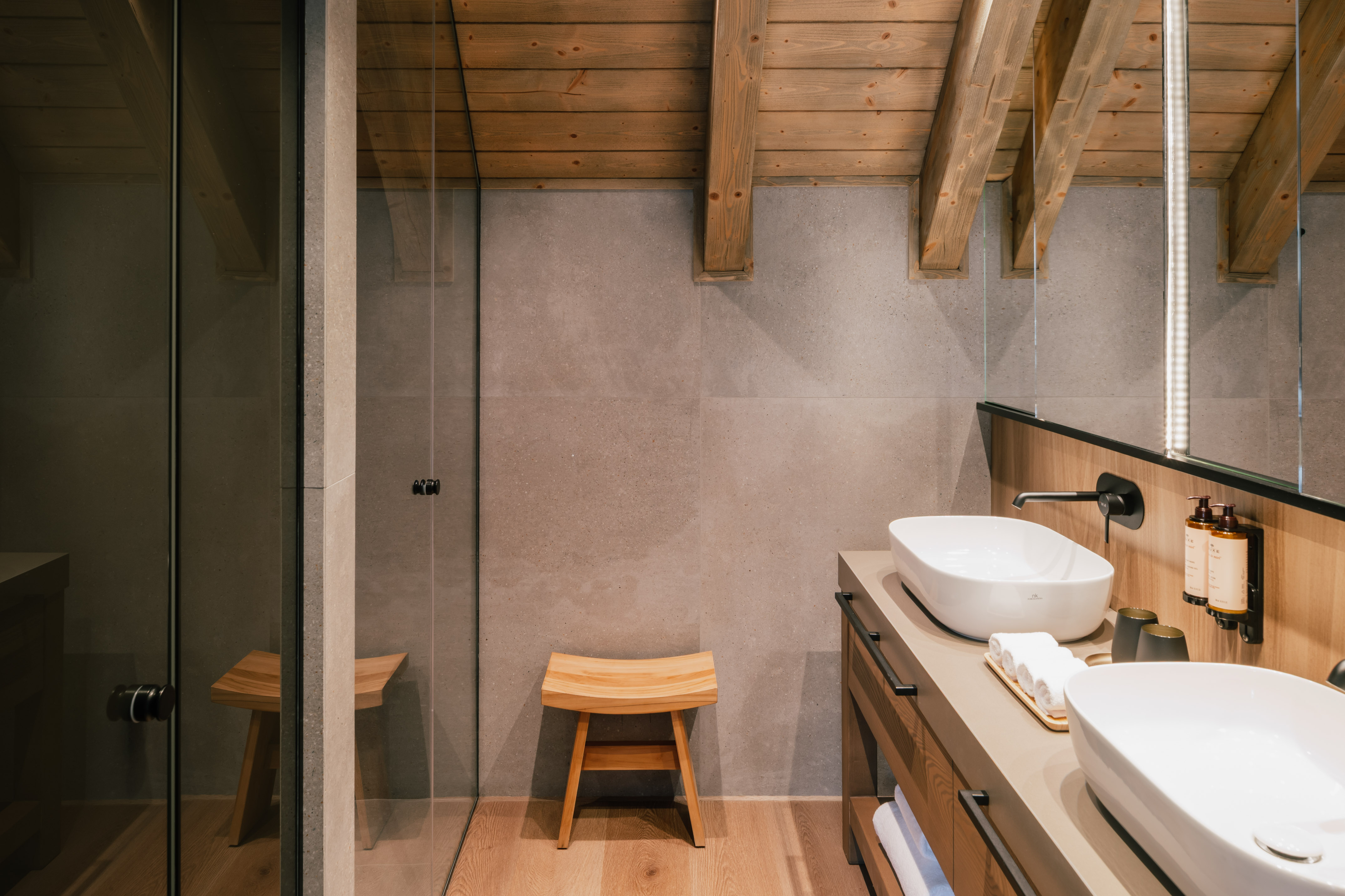 Modern bathroom: wooden beams, concrete walls, double vanity, glass shower.