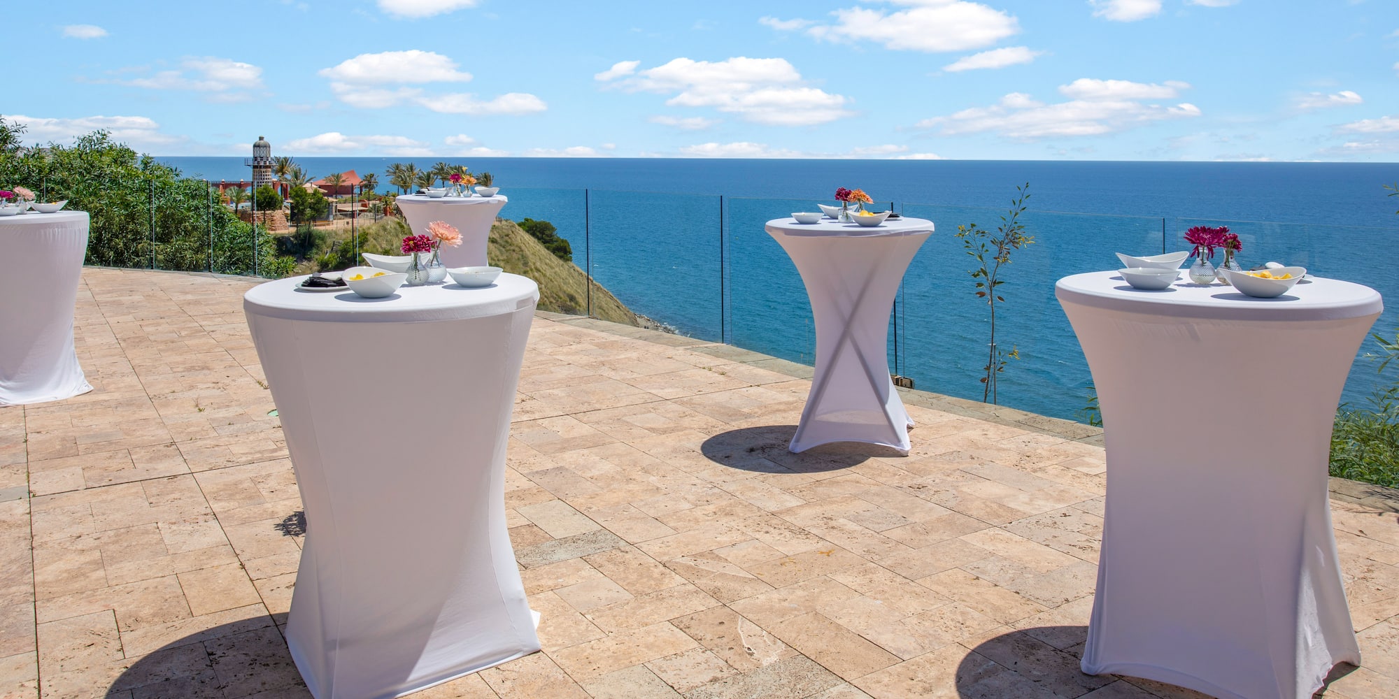 Ocean view terrace with white cocktail tables for an outdoor event.