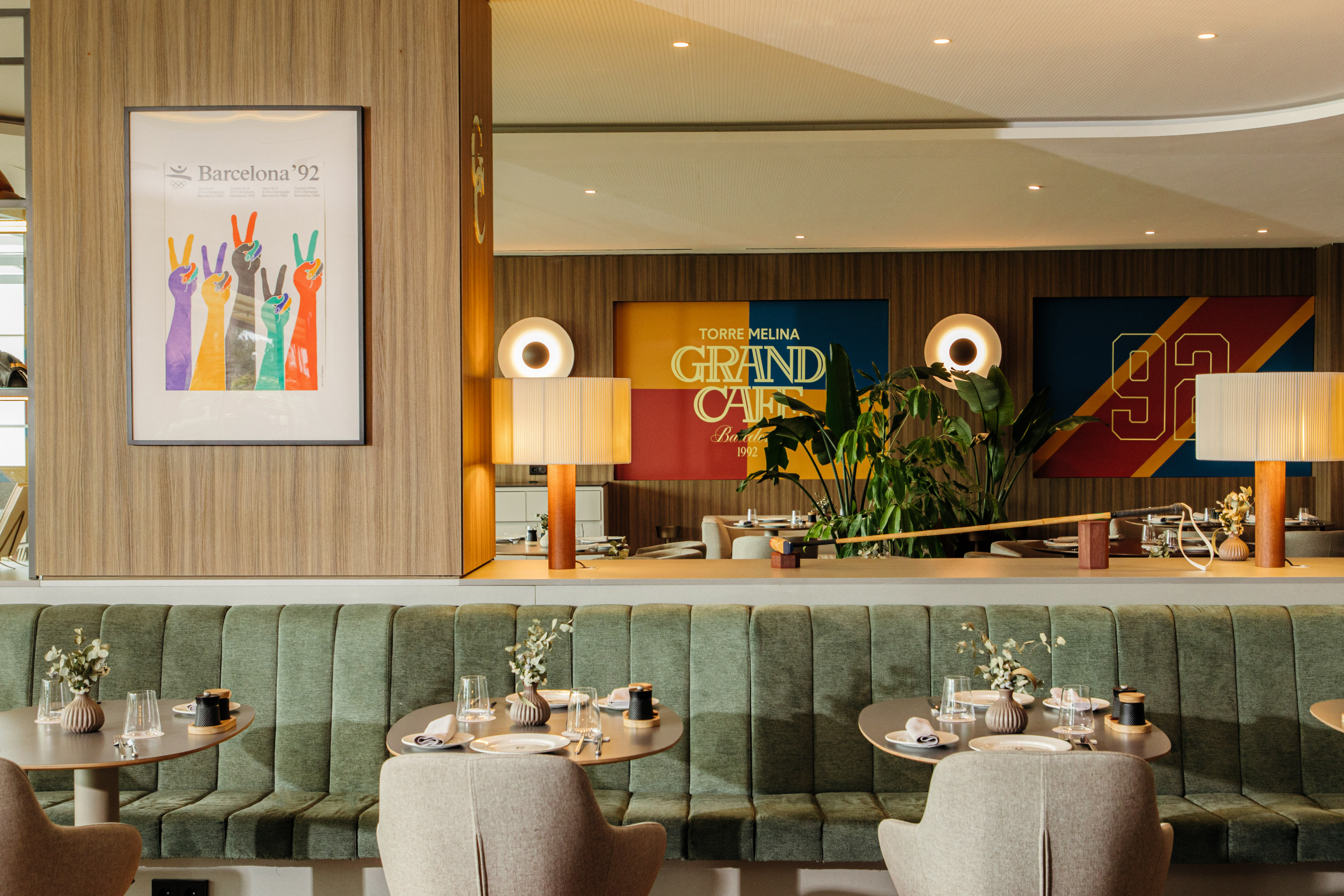 Modern cafe interior, green banquette, set tables, and Barcelona '92 art.