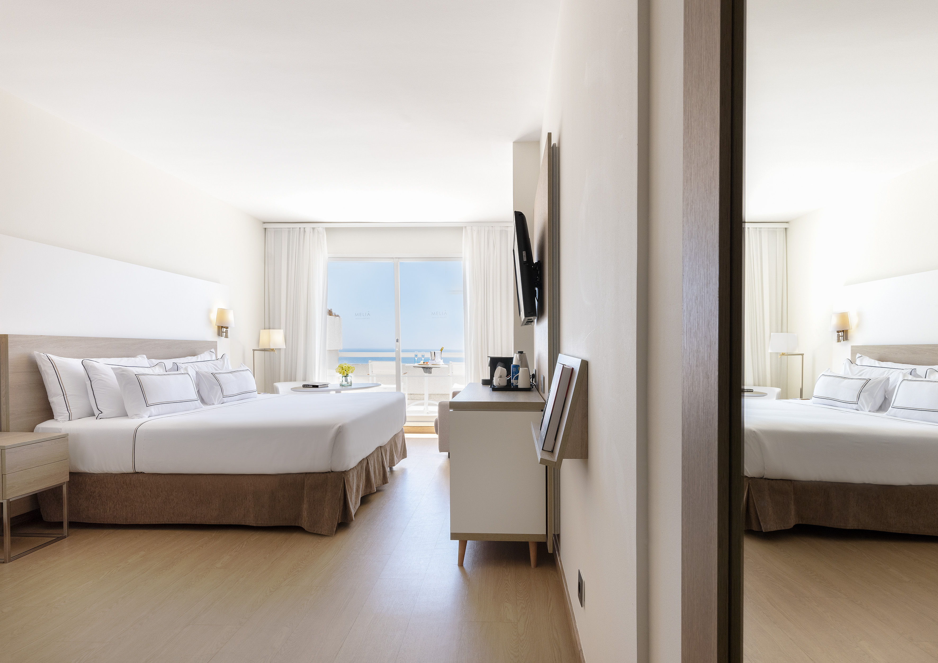 Modern hotel bedroom with ocean view balcony and king-size bed.