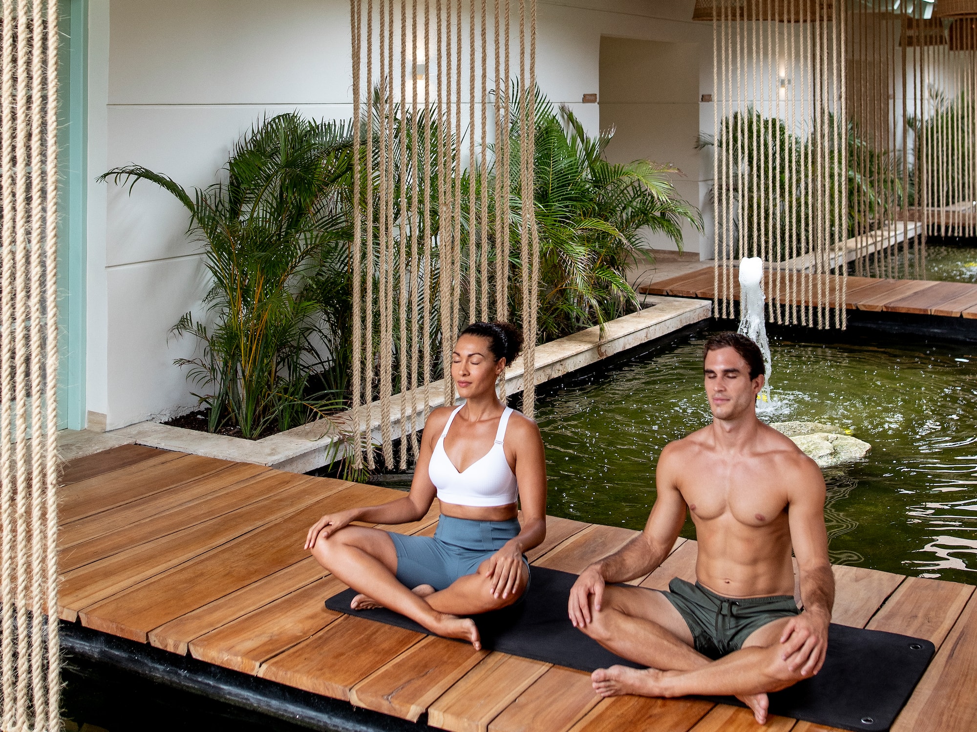 a man and woman sitting on a wooden platform in a room with water