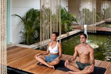 a man and woman sitting on a wooden platform in a room with water