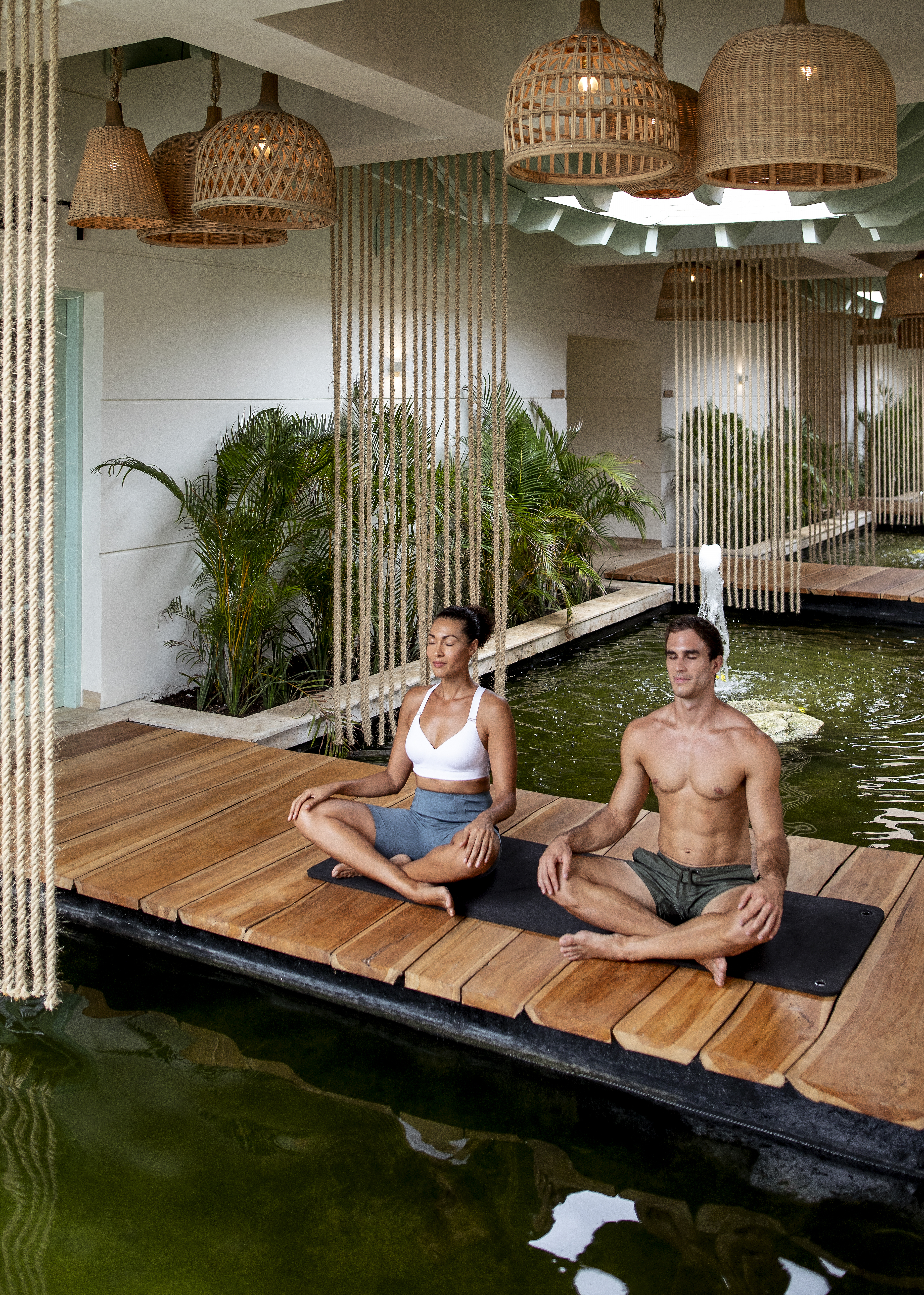 a man and woman sitting on a wooden platform in a room with water