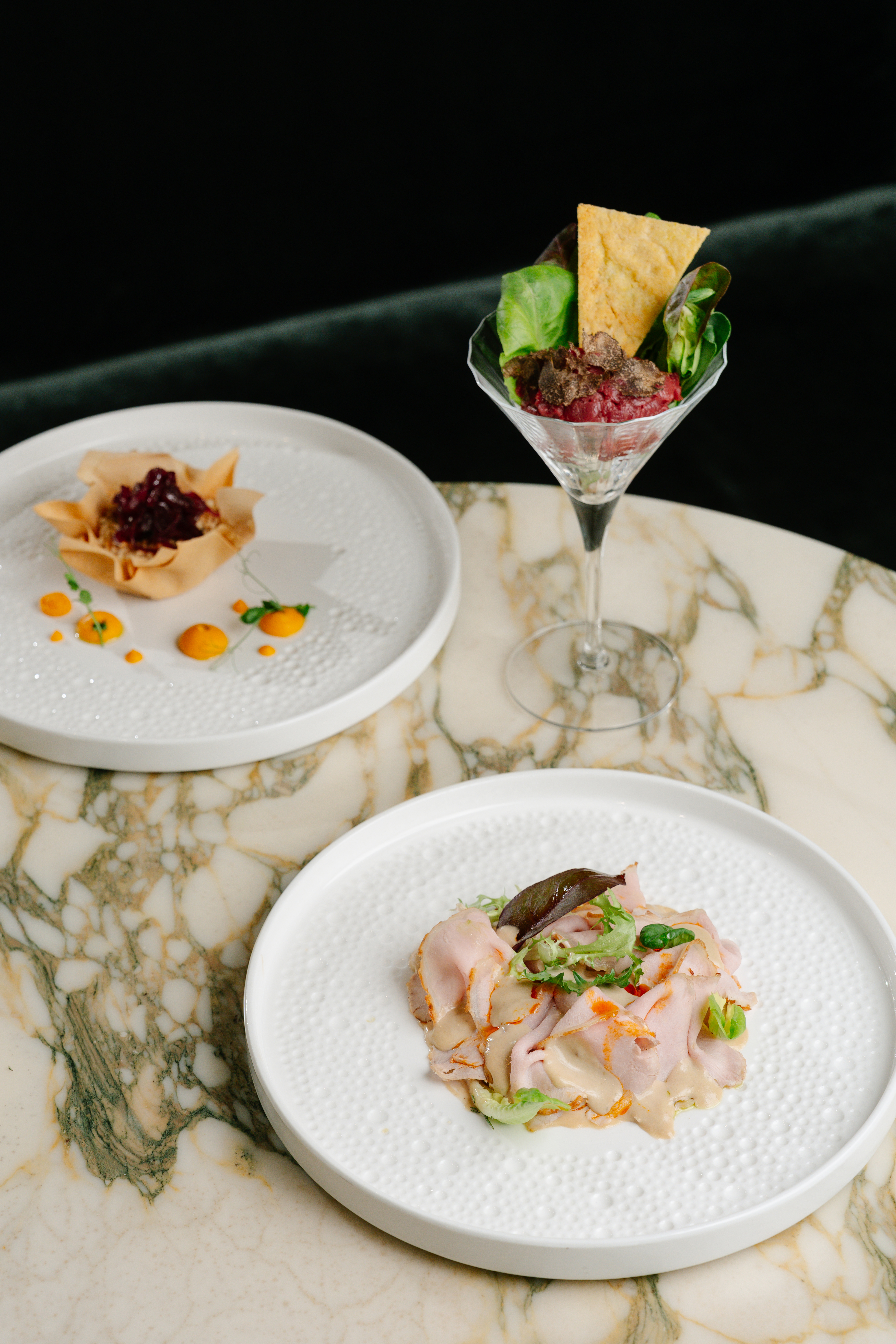 Gourmet appetizers: beet tartare with truffle, savory pastry cup, and sliced meat.