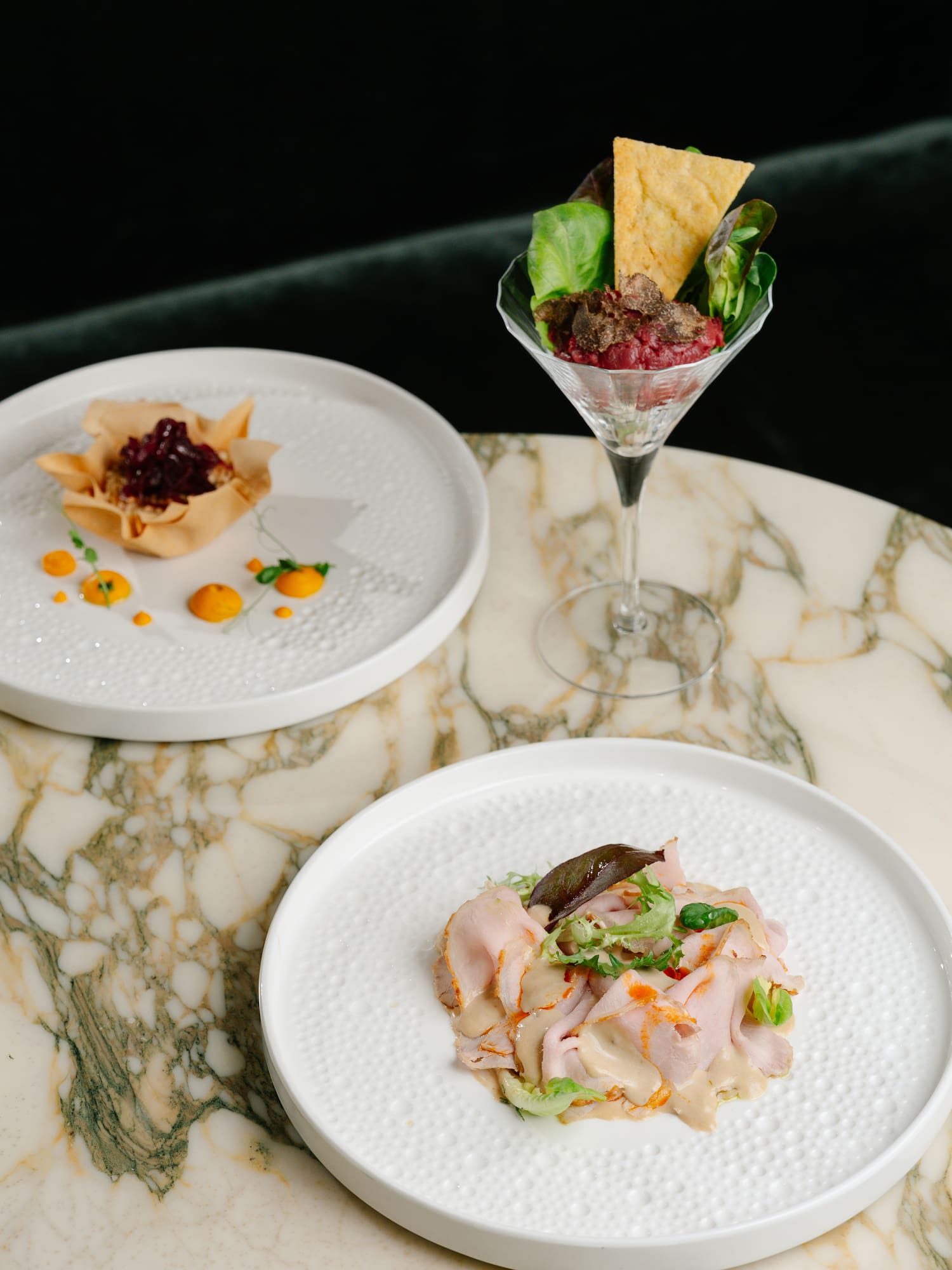 Gourmet appetizers: beet tartare with truffle, savory pastry cup, and sliced meat.