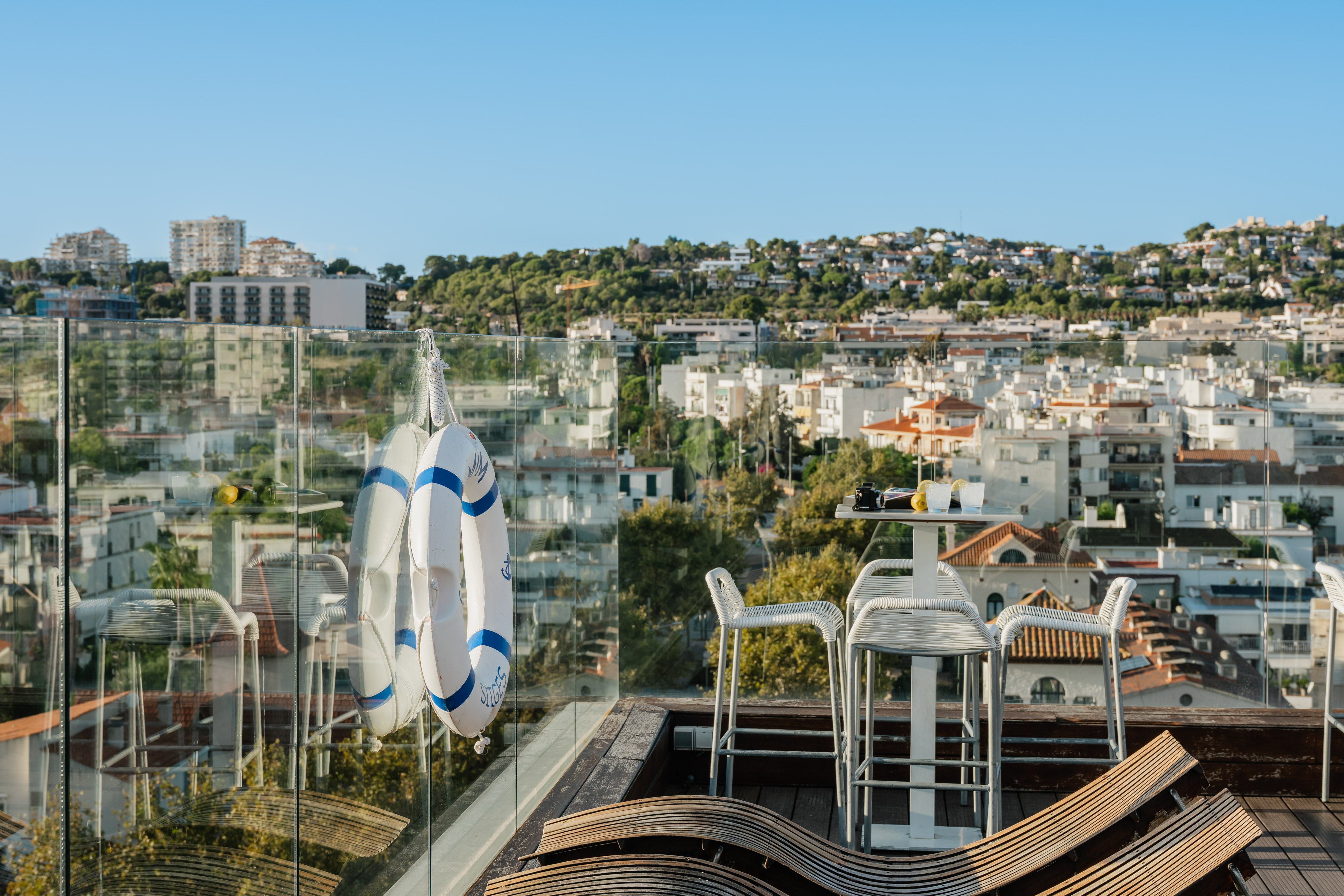 Sitges rooftop terrace with city views, lifebuoy, outdoor bar, and lounge.
