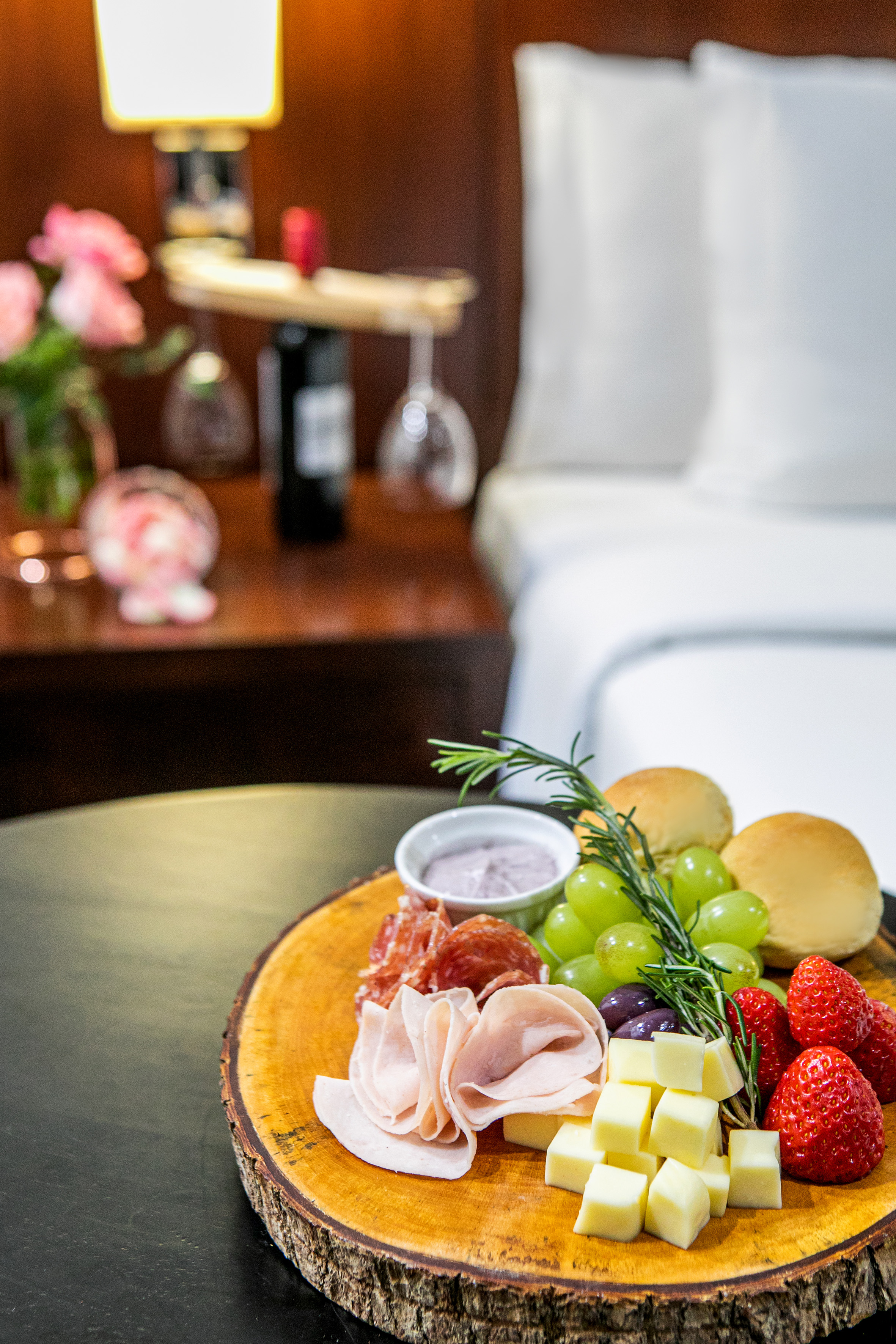 Charcuterie board with cheese, meats, grapes, strawberries in hotel room.