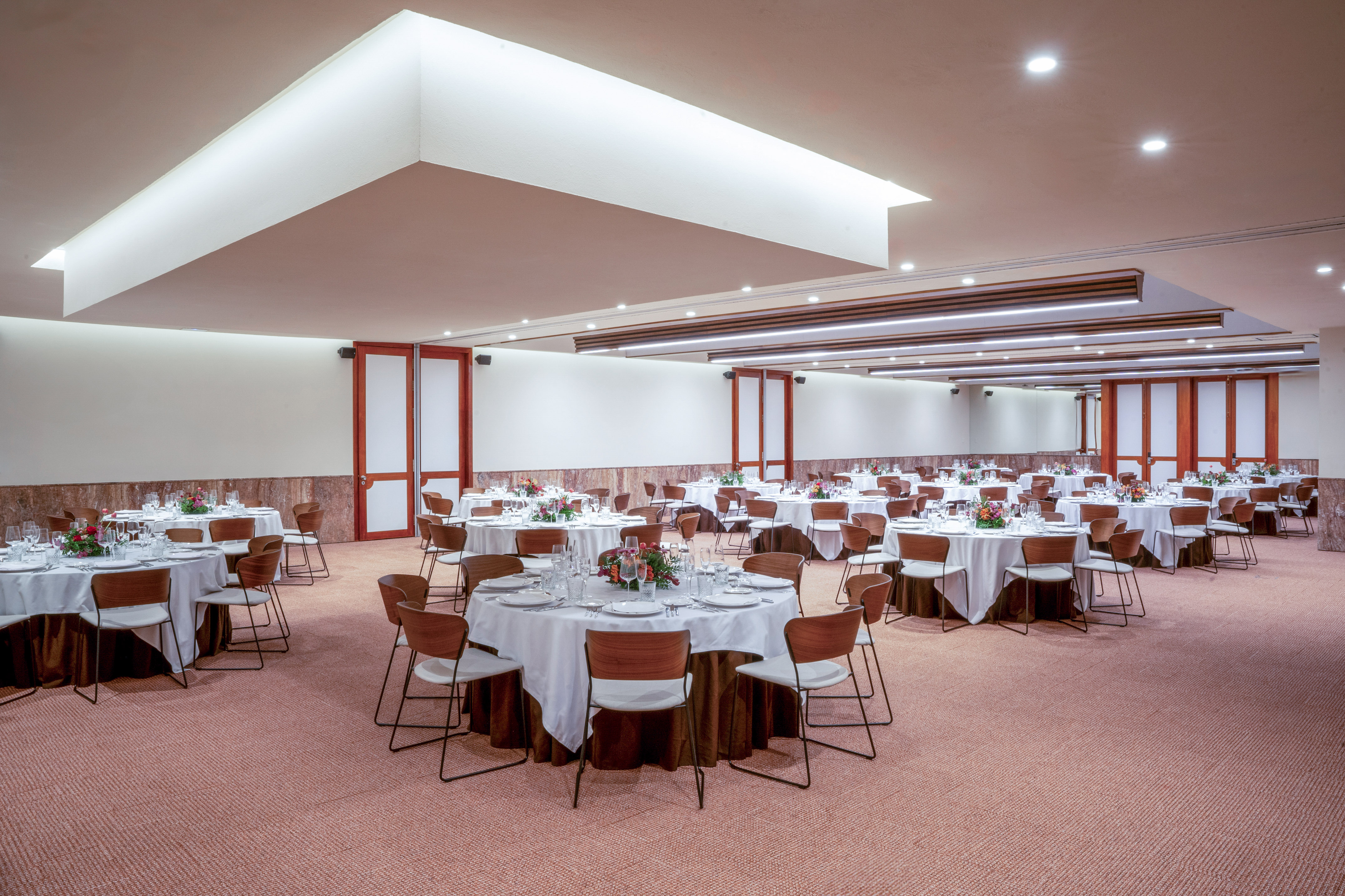 Spacious banquet hall with round dining tables, white tablecloths, and modern decor.