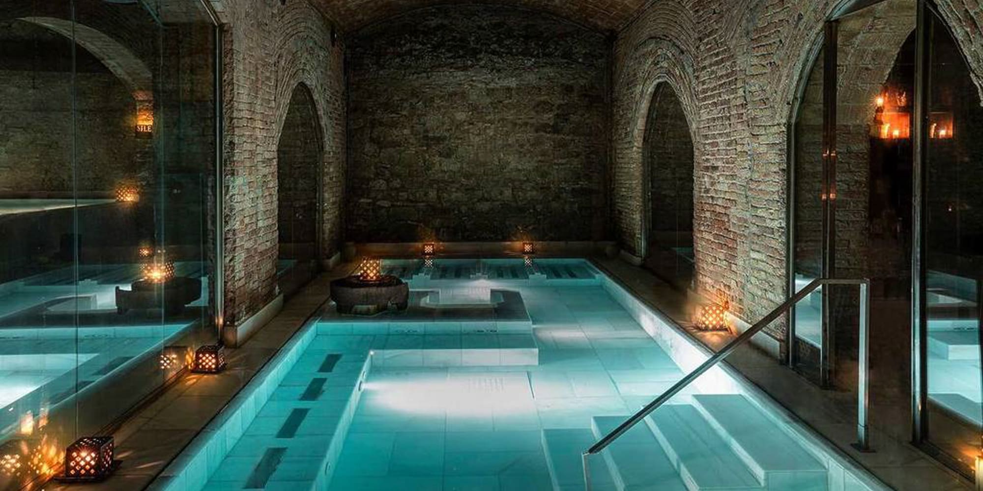 a indoor pool with a staircase and candles with Marrakesh in the background