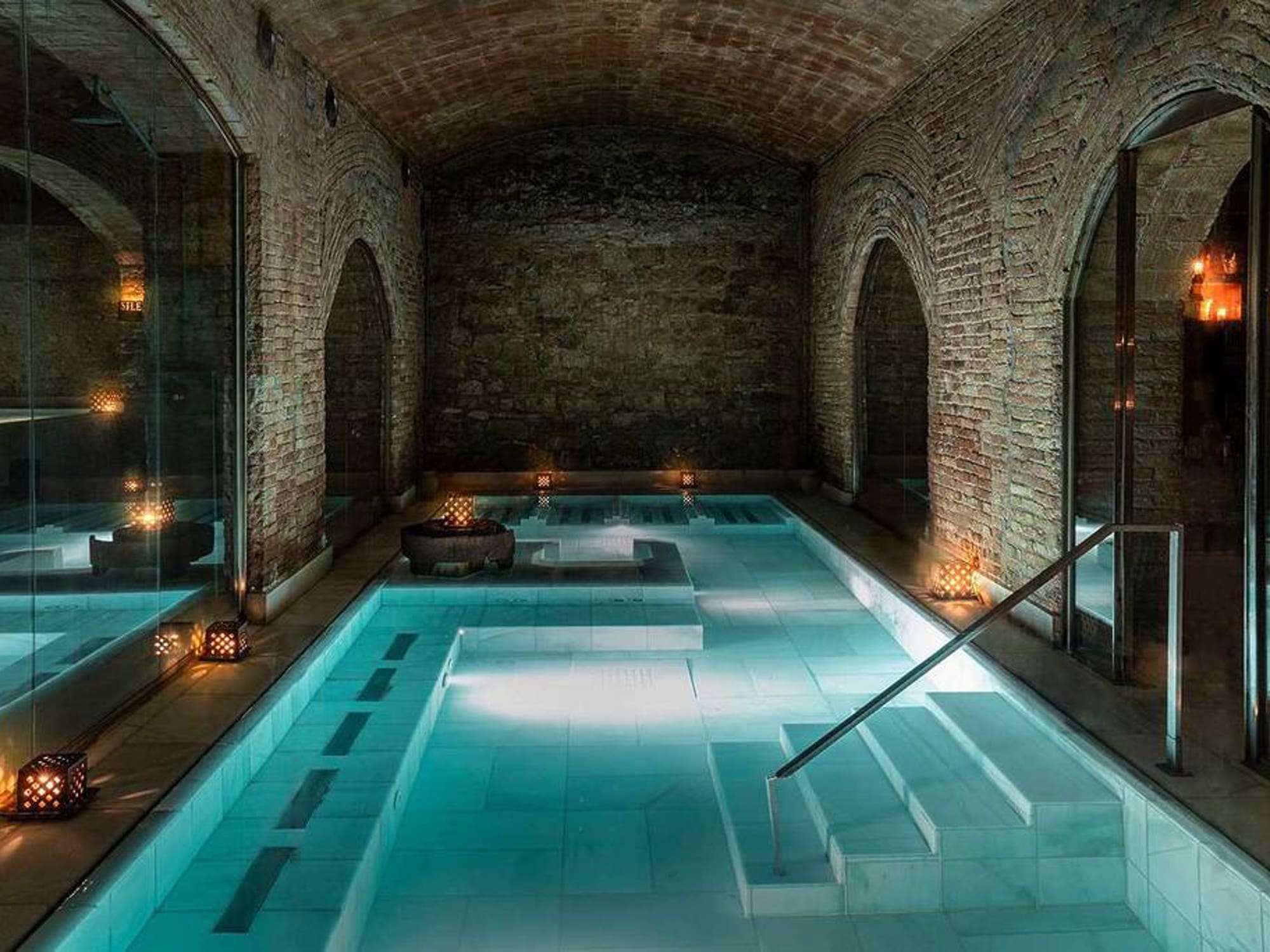a indoor pool with a staircase and candles with Marrakesh in the background