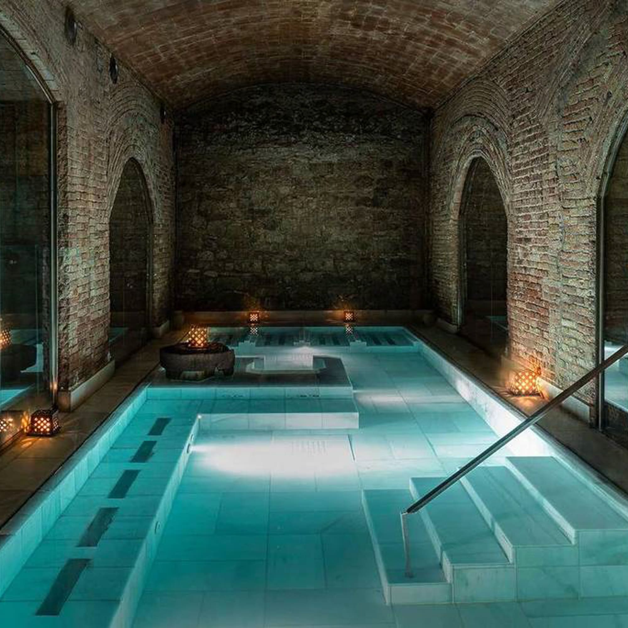 a indoor pool with a staircase and candles with Marrakesh in the background