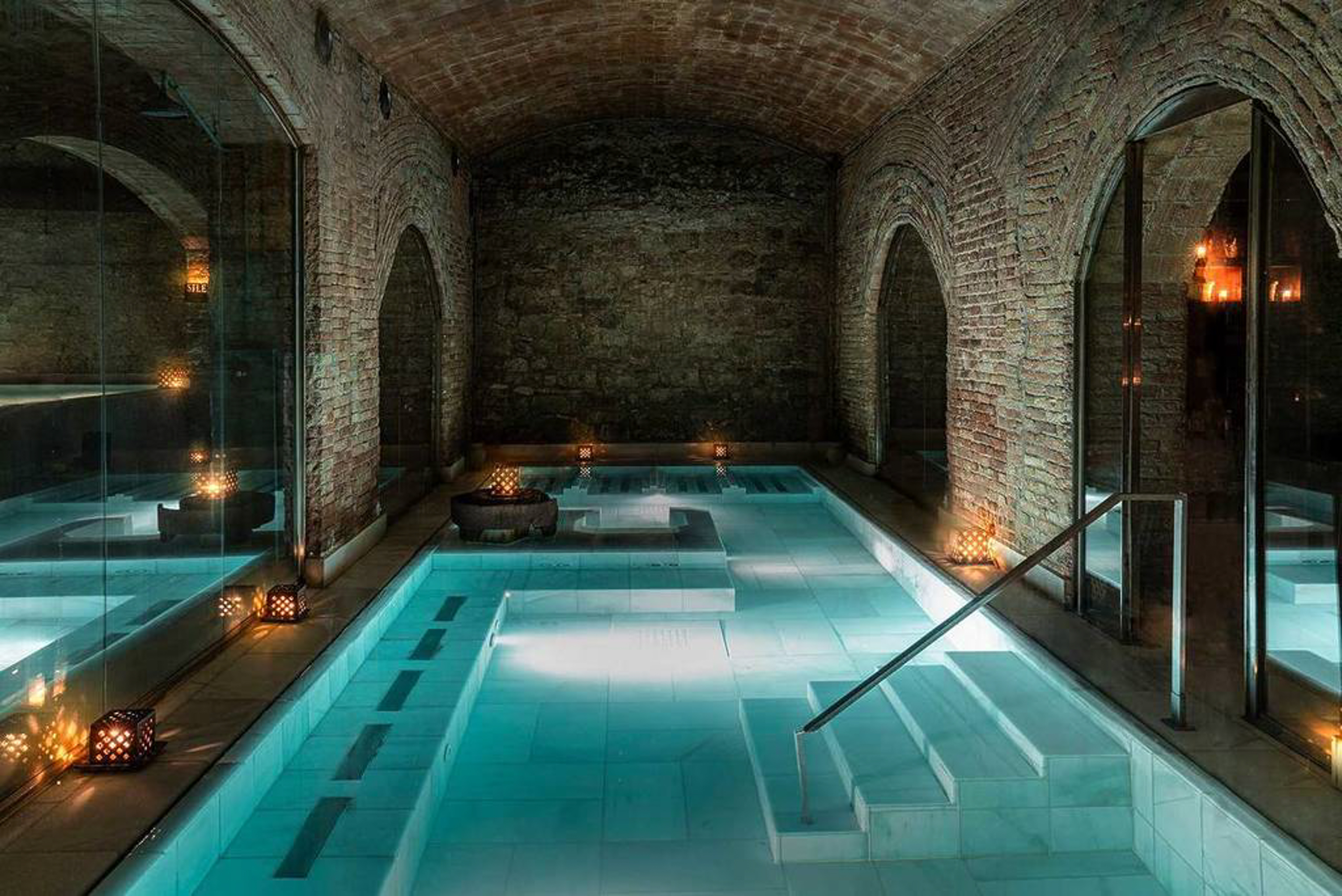 a indoor pool with a staircase and candles with Marrakesh in the background