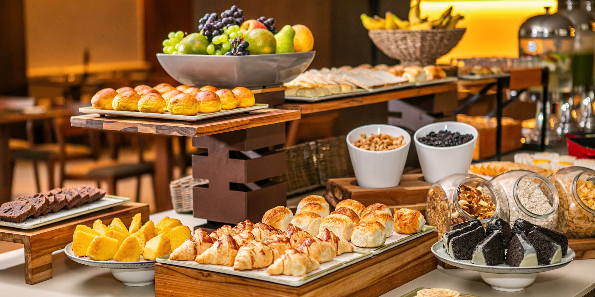 Hotel breakfast buffet with fresh fruit, assorted pastries, bread, and cereals.