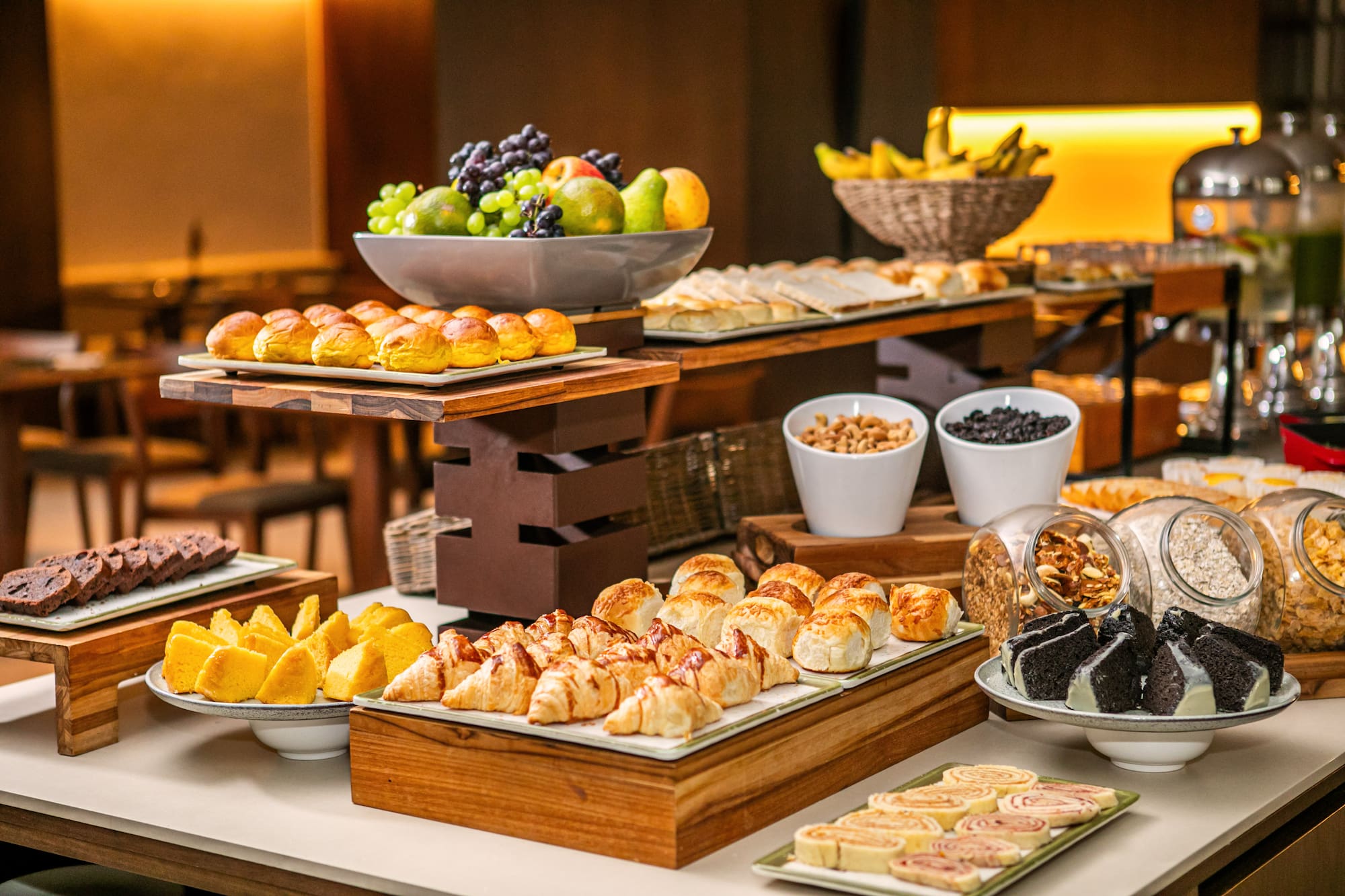 Hotel breakfast buffet with fresh fruit, assorted pastries, bread, and cereals.