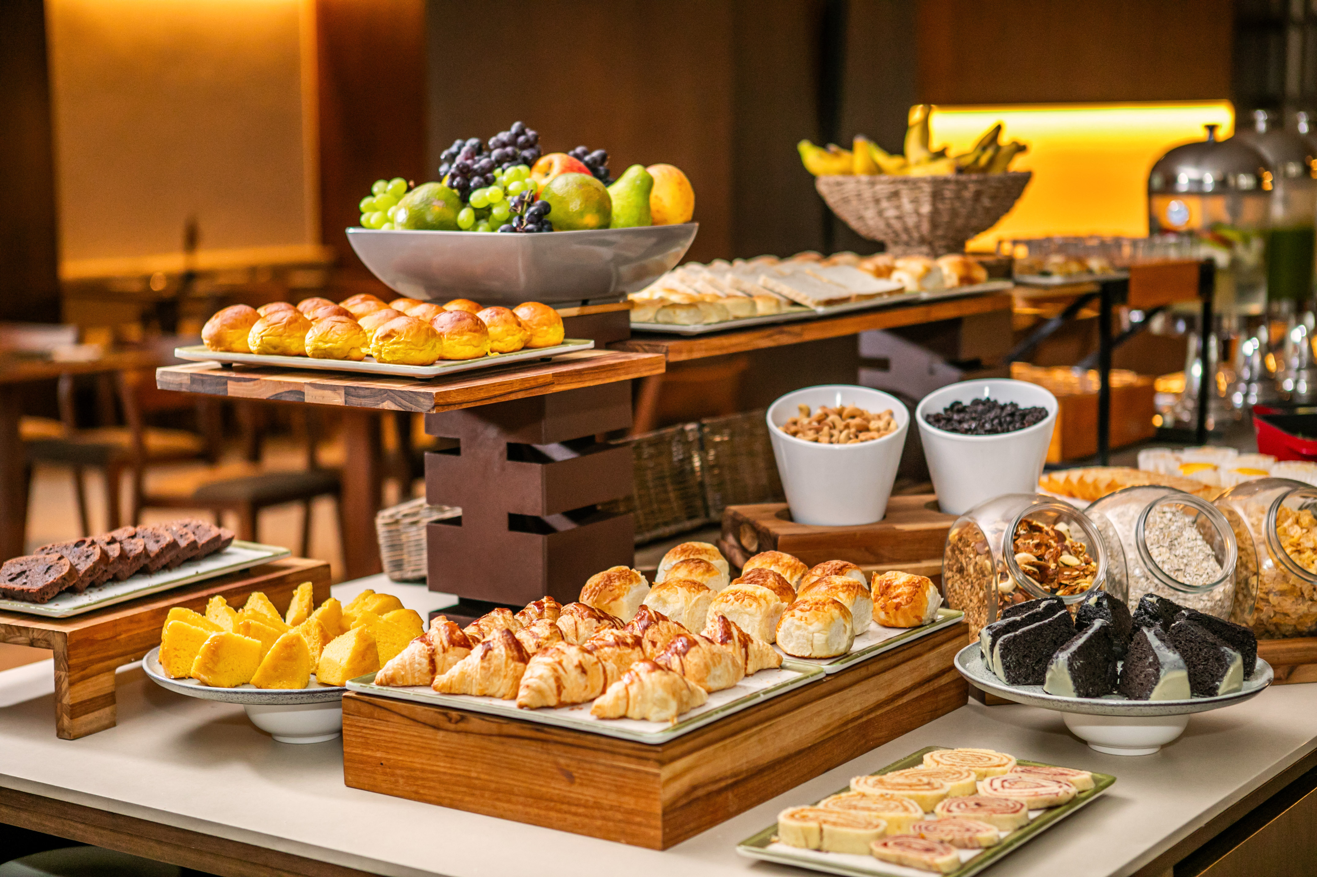 Hotel breakfast buffet with fresh fruit, assorted pastries, bread, and cereals.