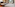 Modern hotel room with king bed, sofa bed, TV, wood floor, and city view window.