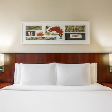 a bed with white sheets and a painting above it