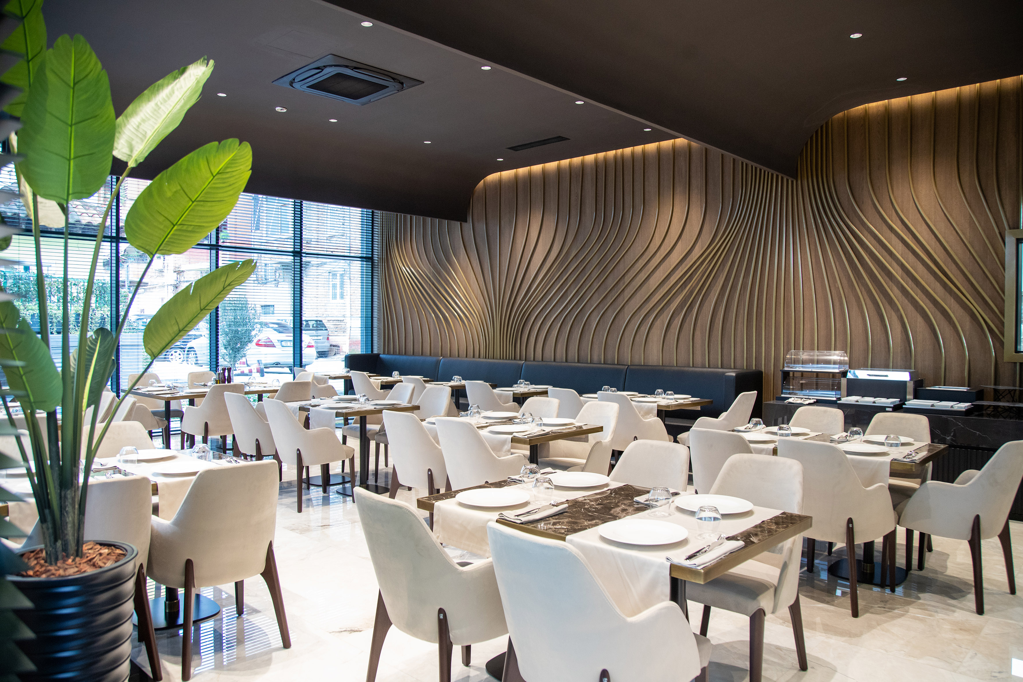 Modern restaurant dining area, set tables, white chairs, wavy wooden wall.