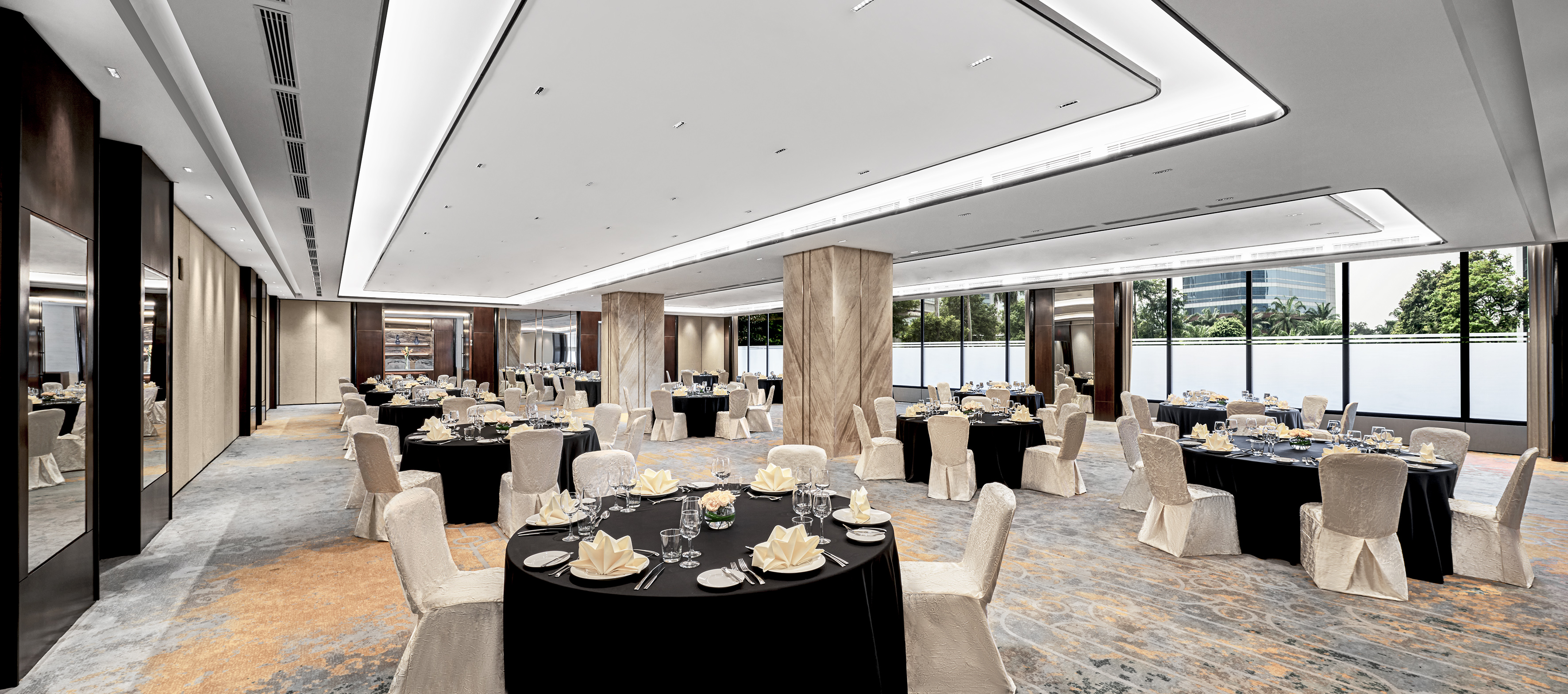 Modern event space with round tables, black linens, and white chairs.