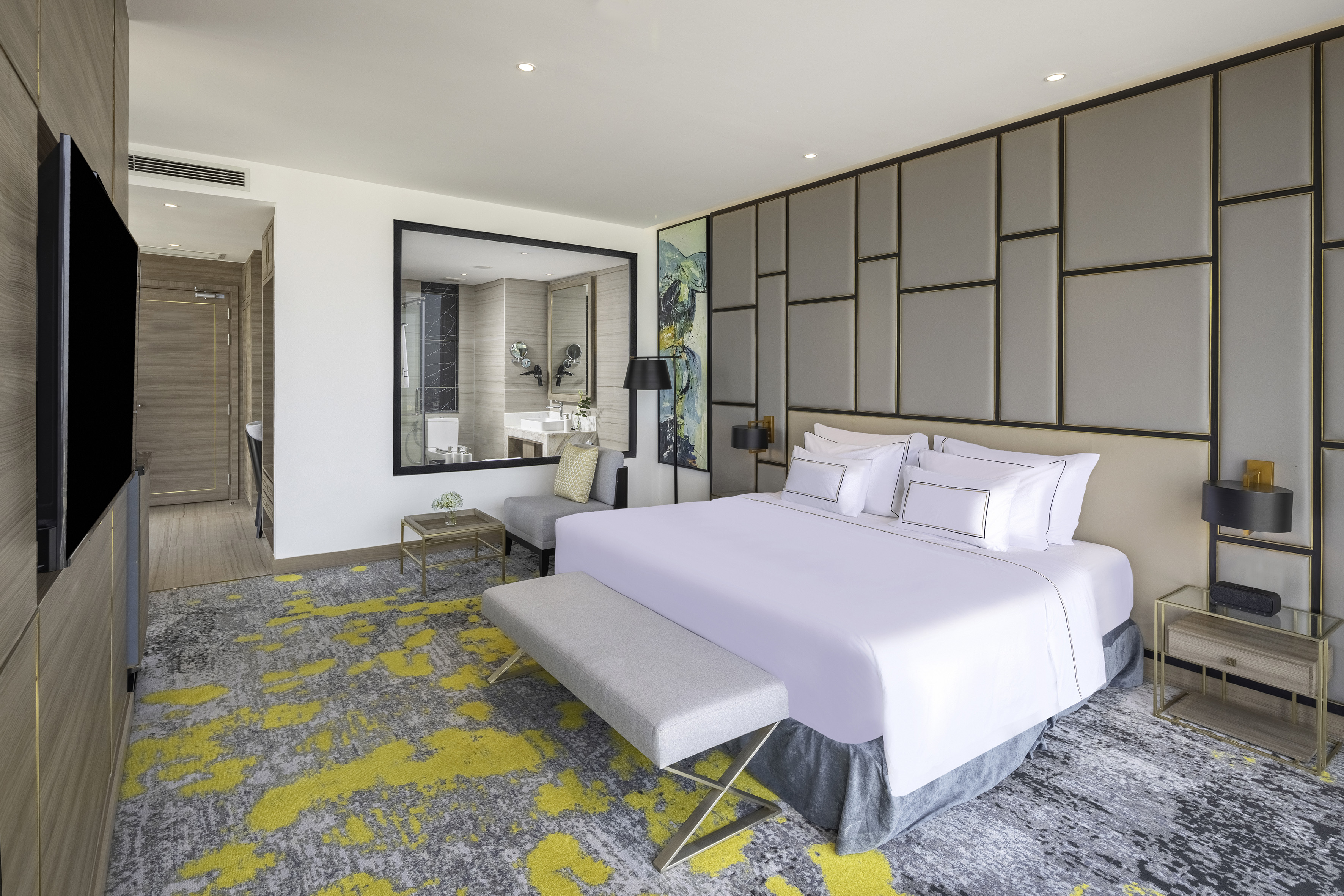 Luxury hotel bedroom suite, king bed, vibrant yellow carpet, modern decor.