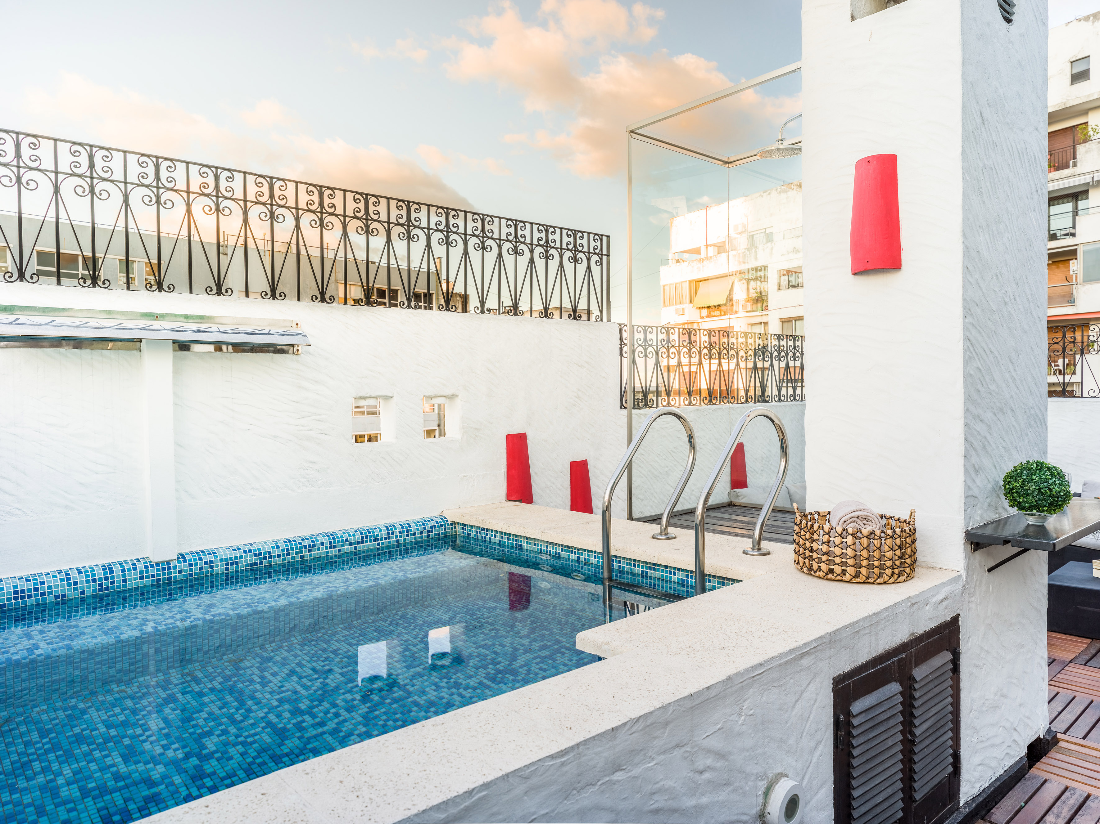 Rooftop terrace pool with blue tiles, white textured walls, and city view. - Buitenervaringen - Melia Recoleta Plaza, Buenos Aires